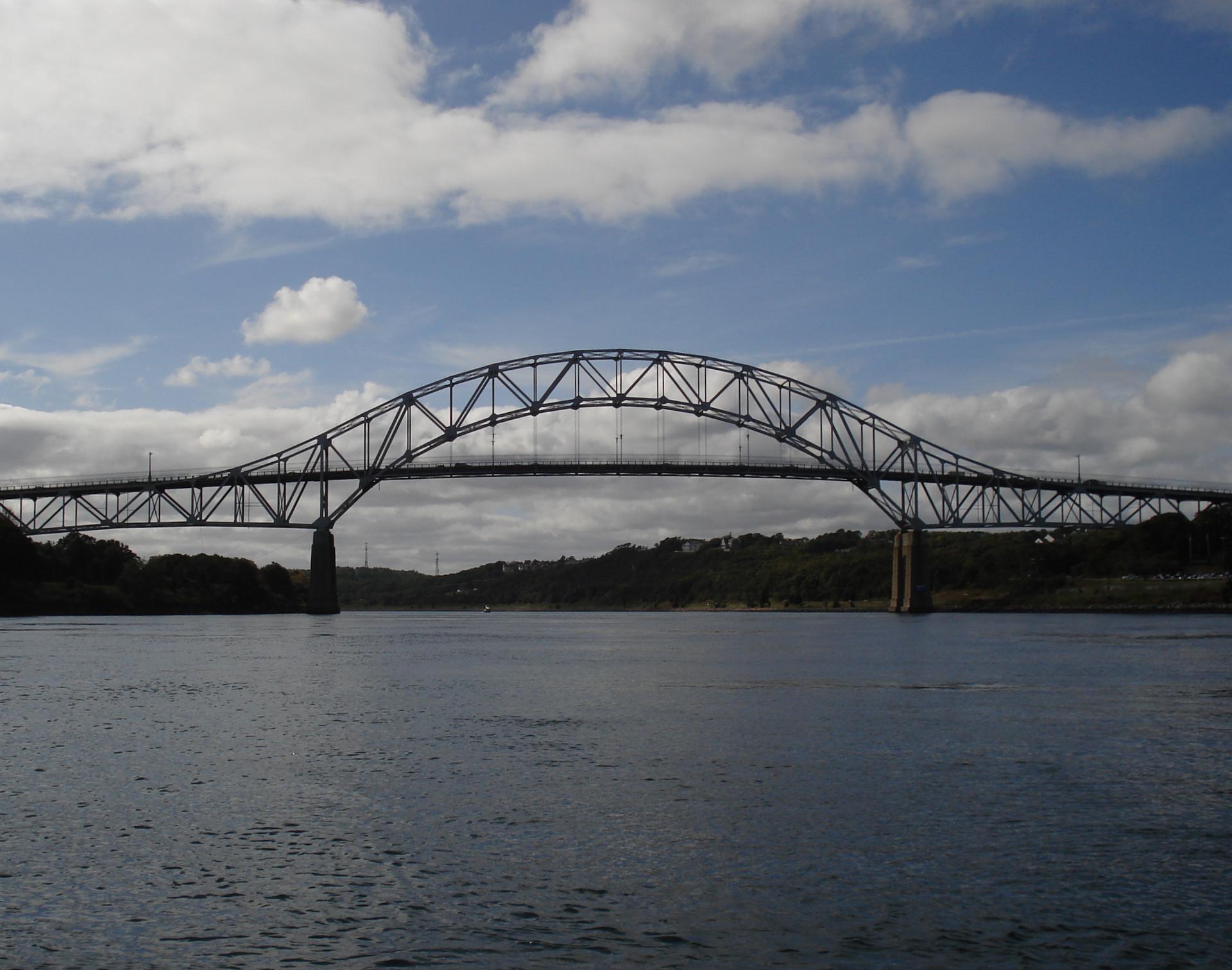 A large steel arched bridge spans a wide body of water.