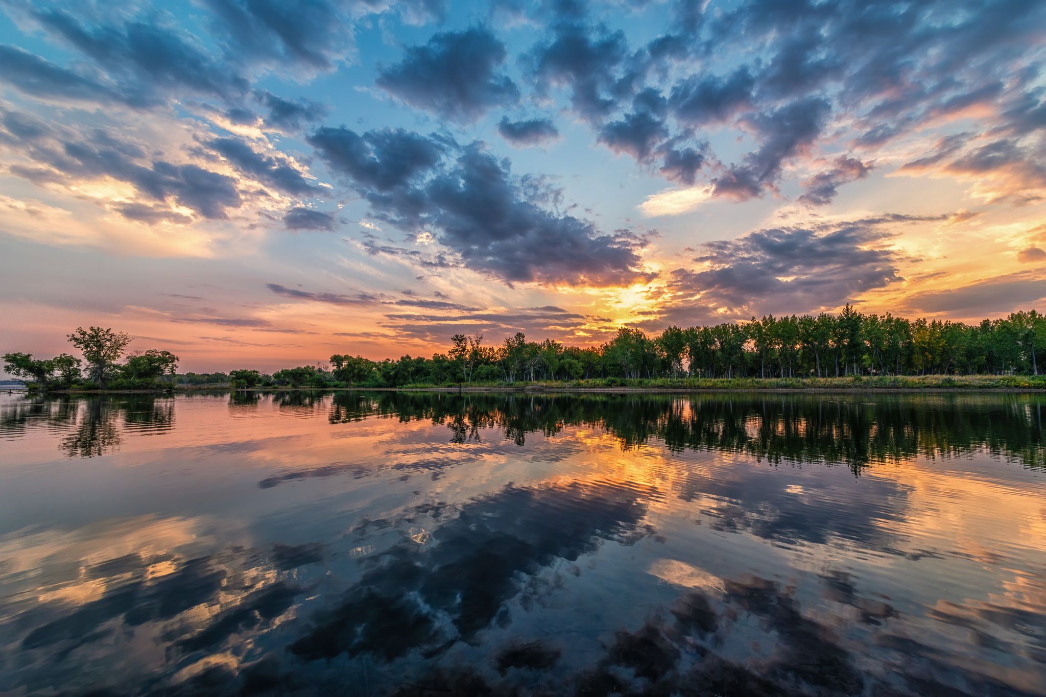 Vibrant sunset sky reflected in calm water with a distant treeline. - Colorado Front Range Trail: Chatfield State Park Loop