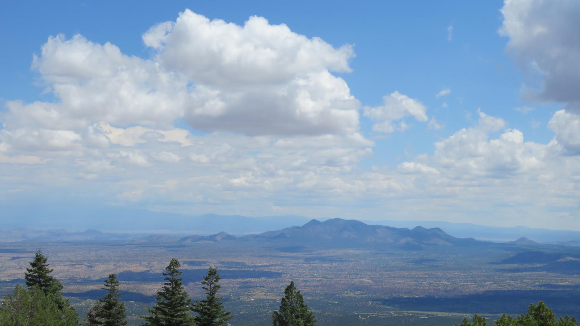 Expansive view of a distant mountain range and valley under a partly cloudy sky.