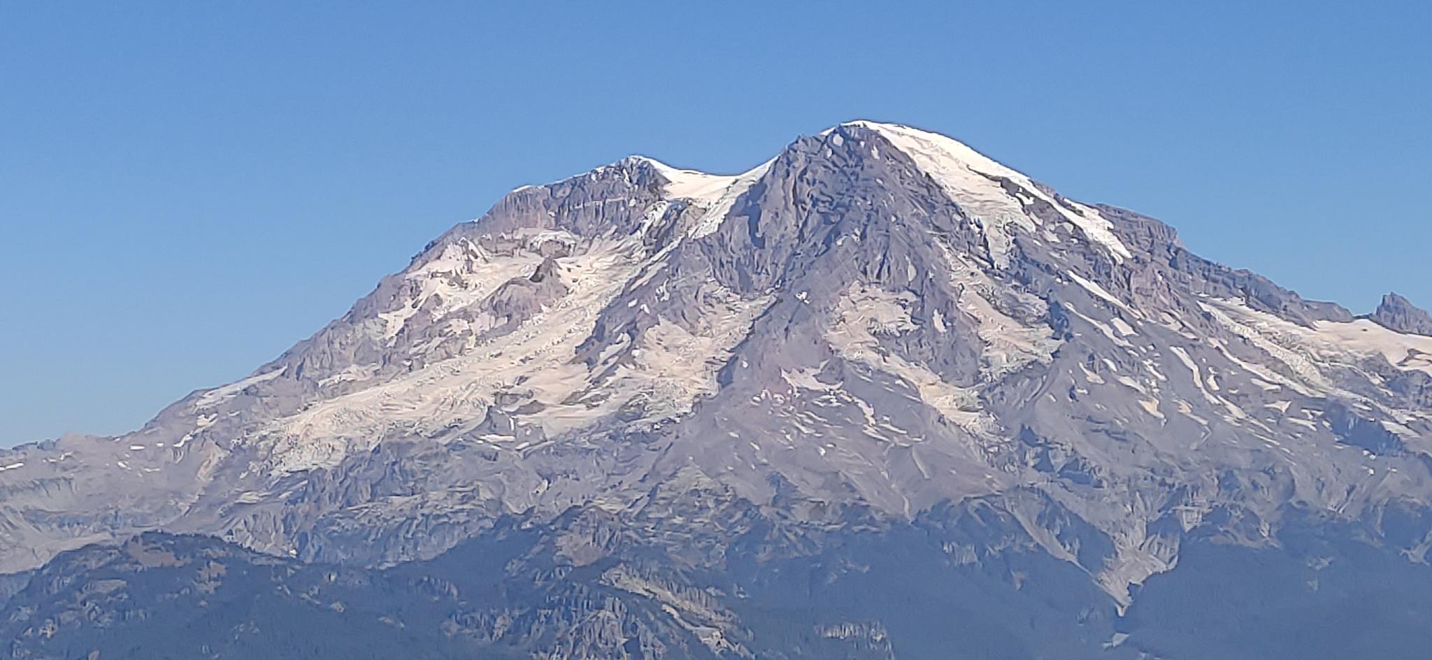 Majestic snow-capped mountain peak under a clear, bright blue sky.