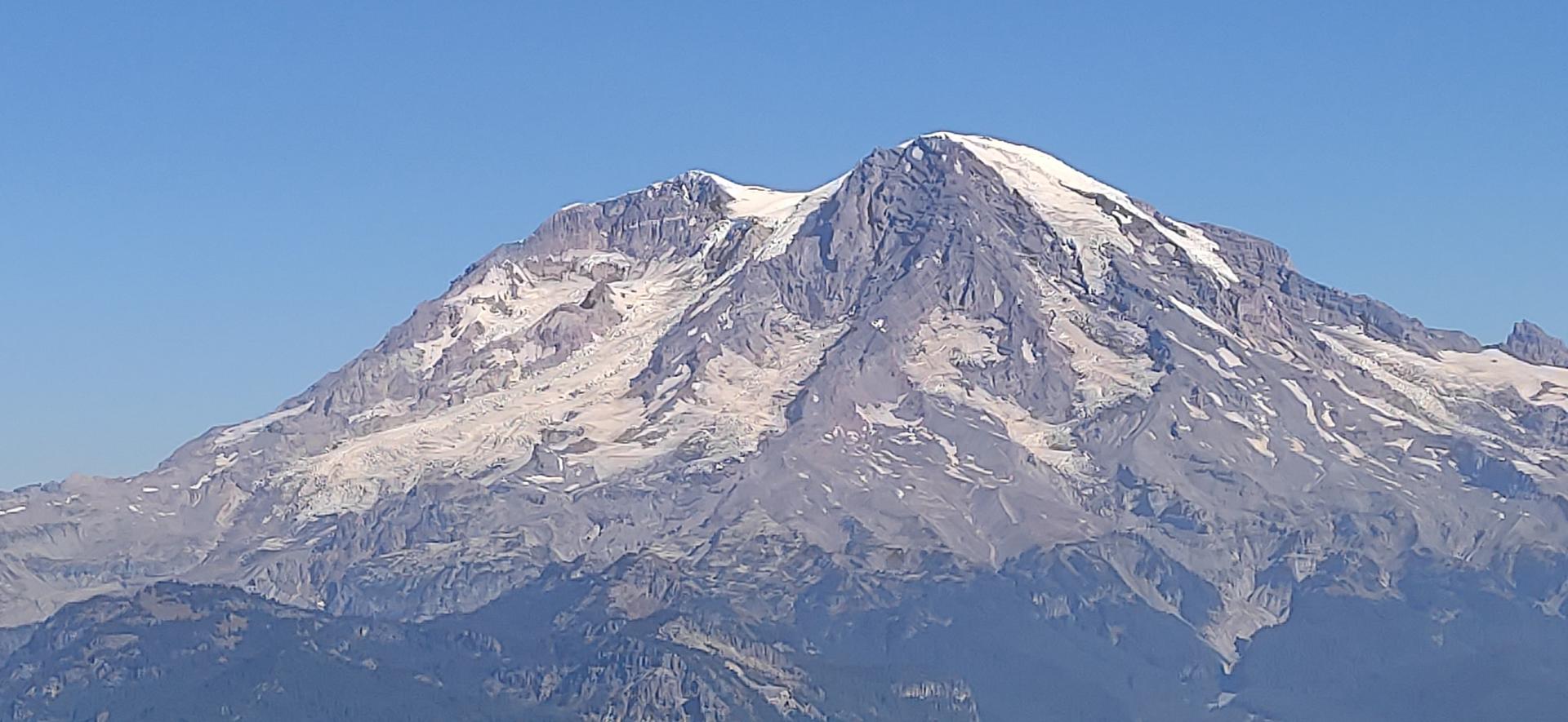Majestic snow-capped mountain peak under a clear, bright blue sky.