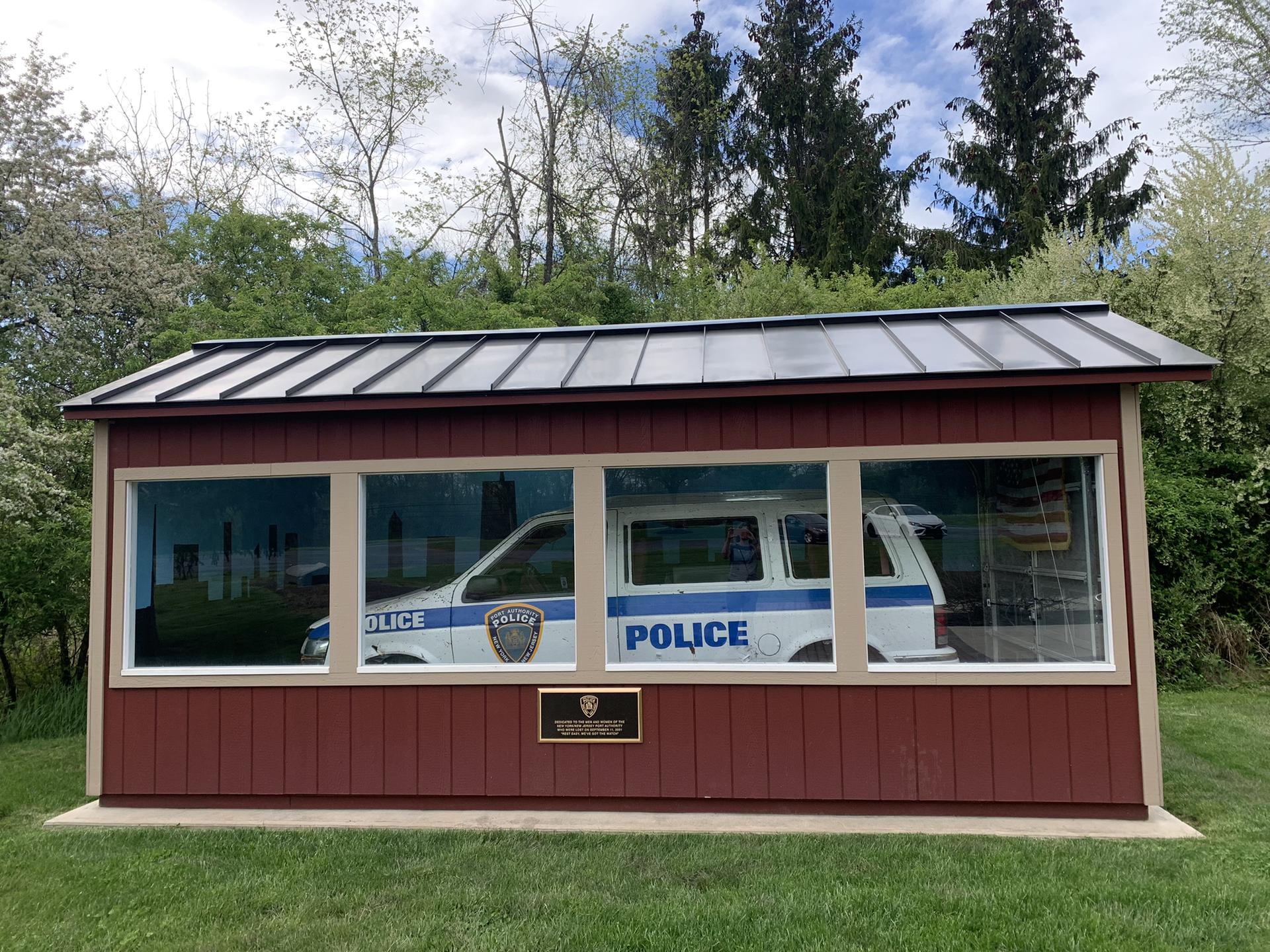 A red shed with large windows displays a white police vehicle inside.