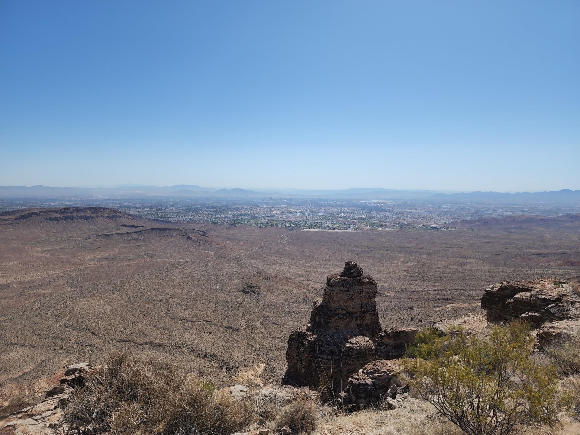 Vast desert landscape from a high viewpoint under a clear blue sky.