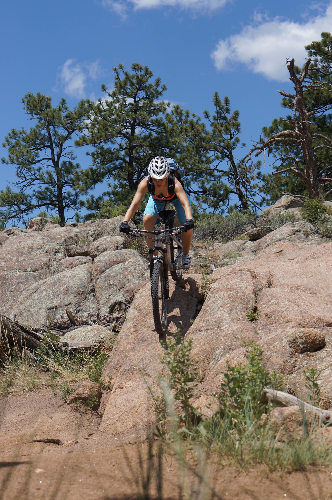 Cyclist in a helmet riding a mountain bike down a rocky slope.