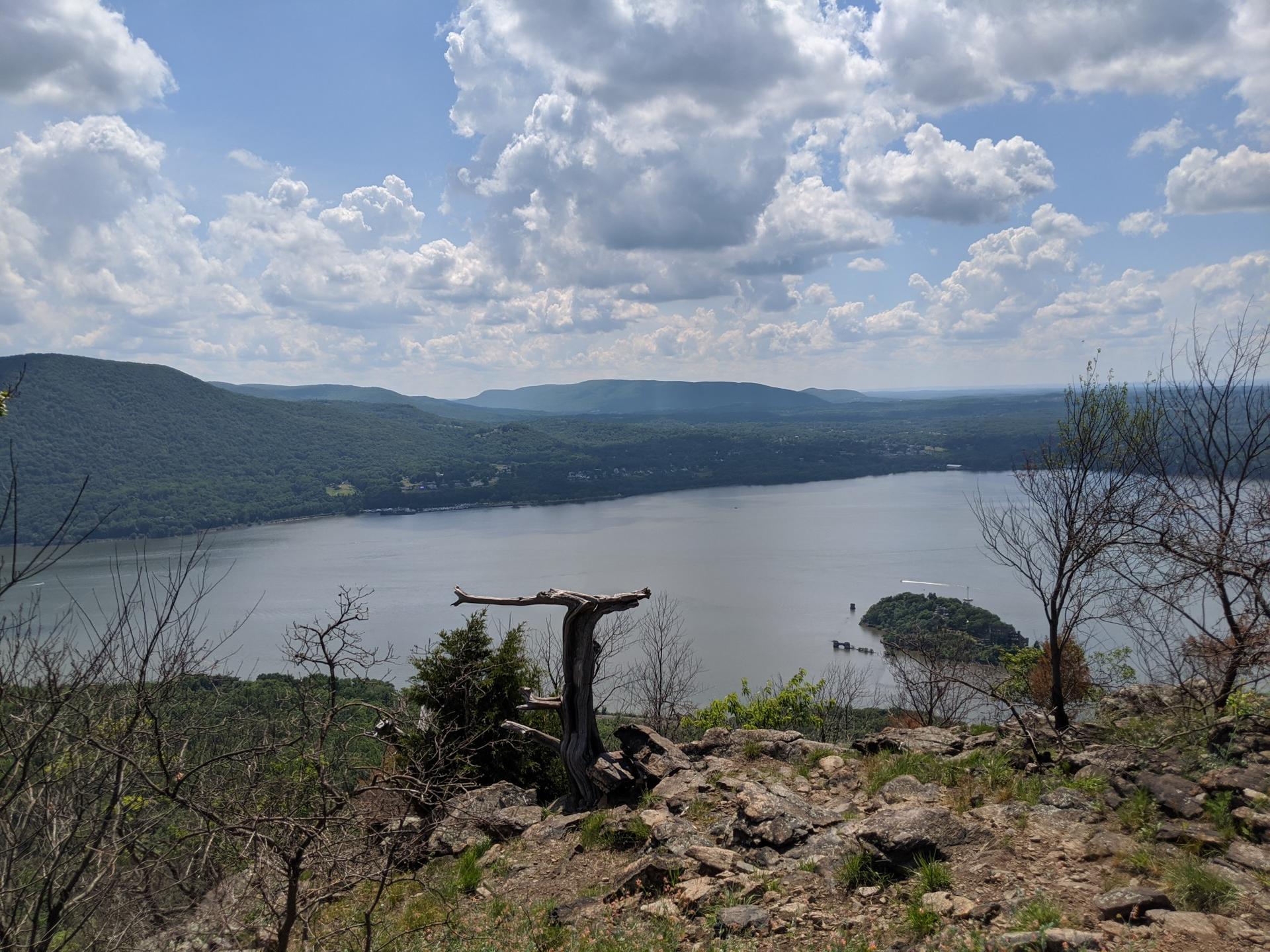 Lake surrounded by green mountains under a partly cloudy sky, with a small island.