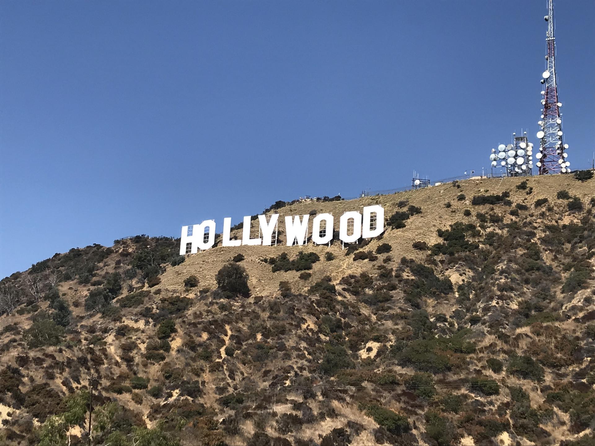 Large white letters on a dry, brushy hill under a clear blue sky.