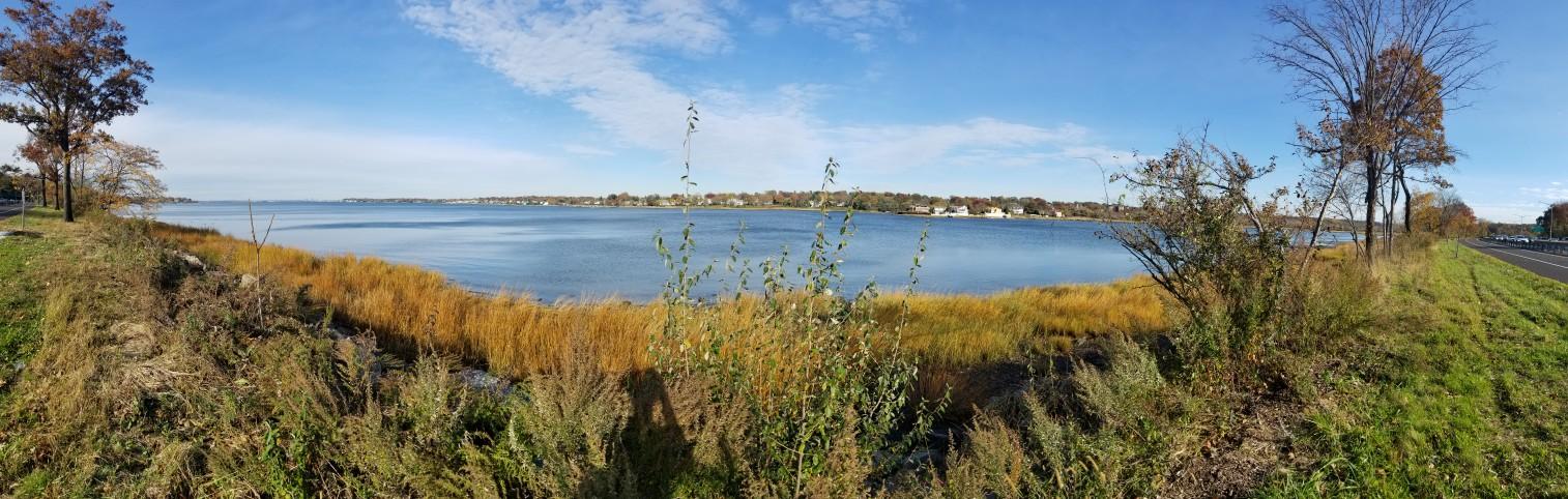 Panoramic view of a wide body of water with distant houses.