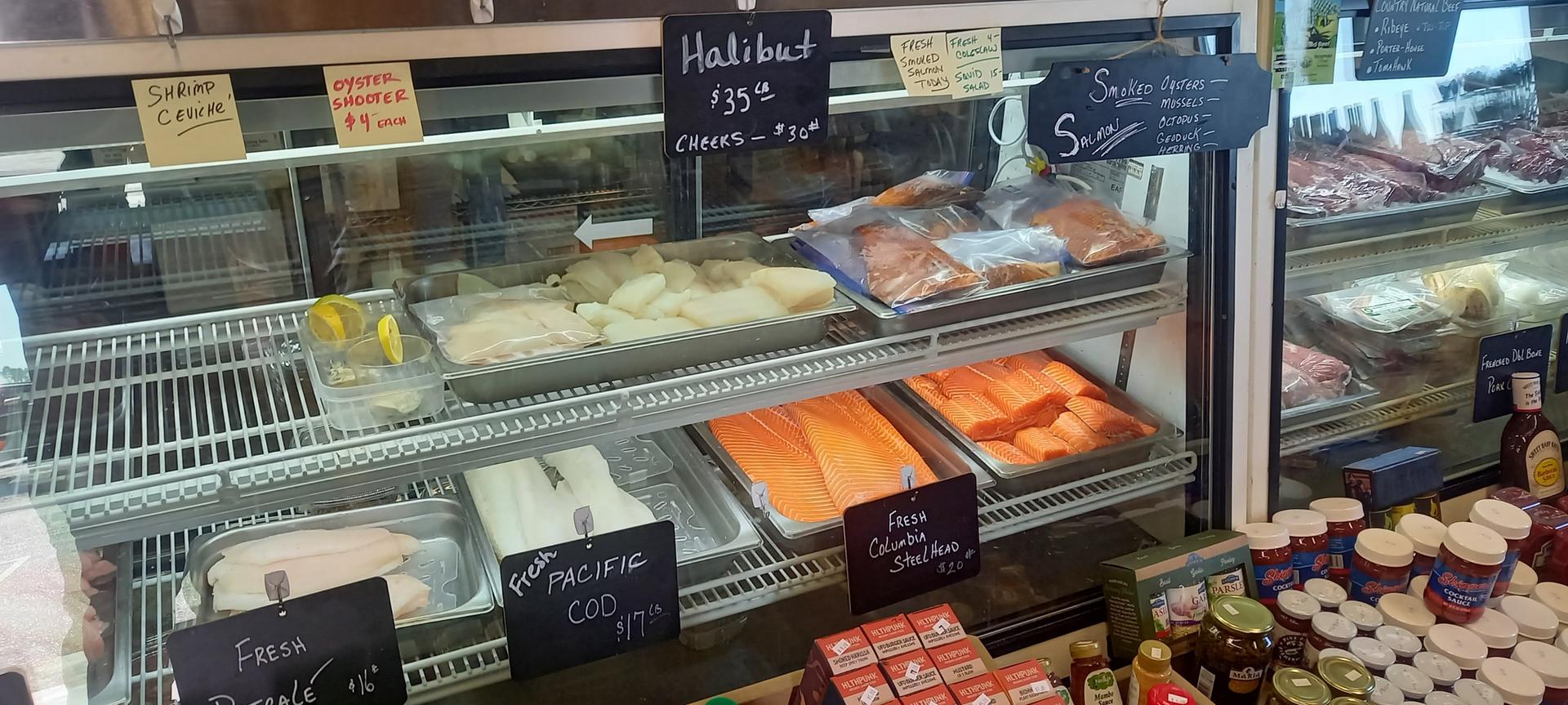 Display case filled with fresh seafood, including halibut and salmon.