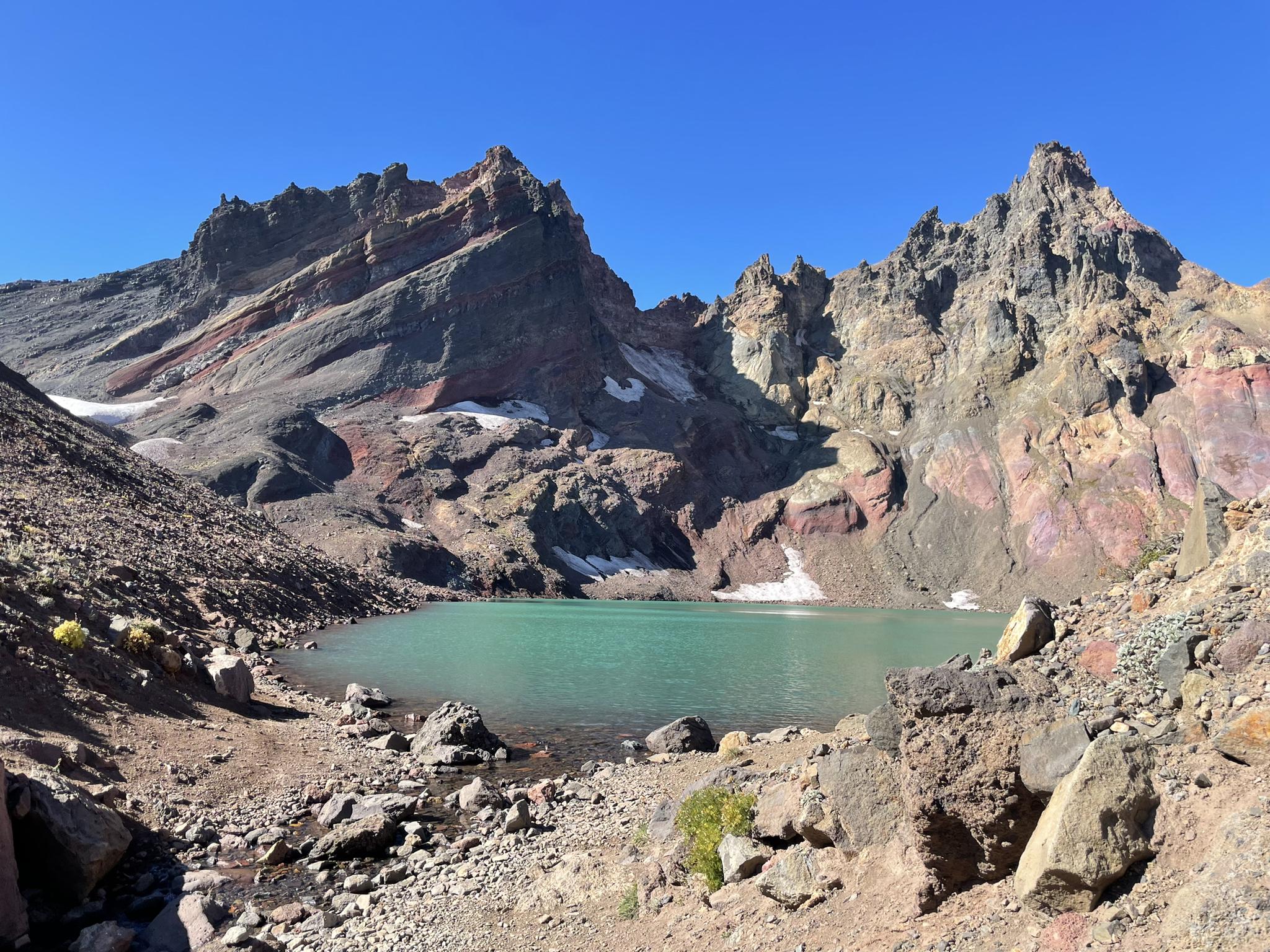 Turquoise alpine lake surrounded by rugged, rocky mountains under clear sky.