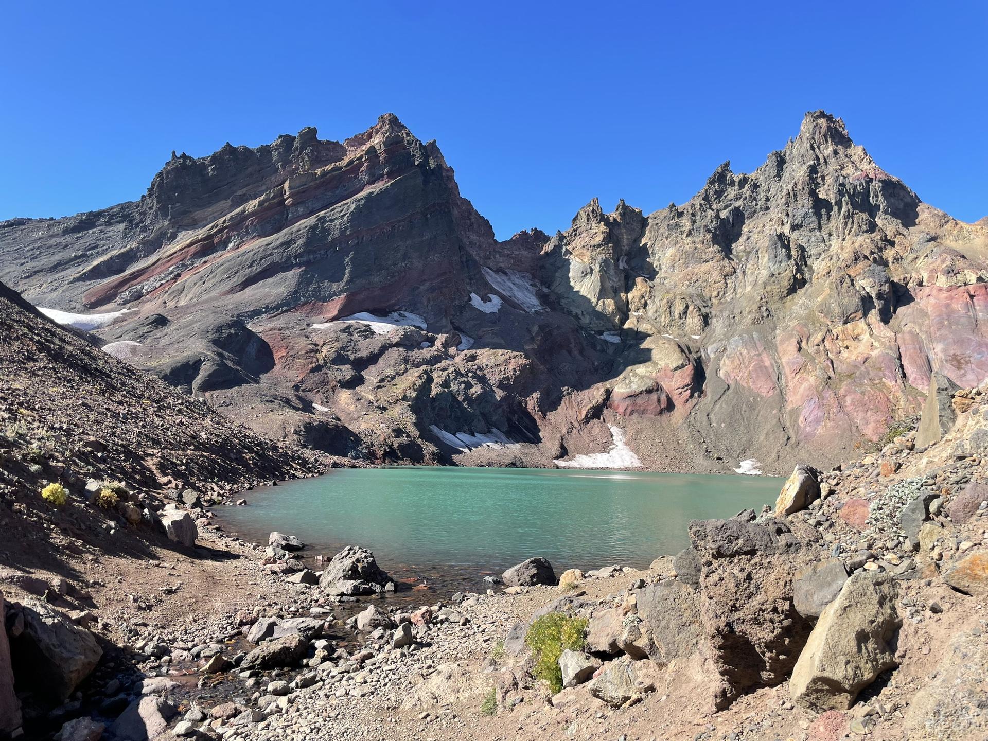 Turquoise alpine lake surrounded by rugged, rocky mountains under clear sky.