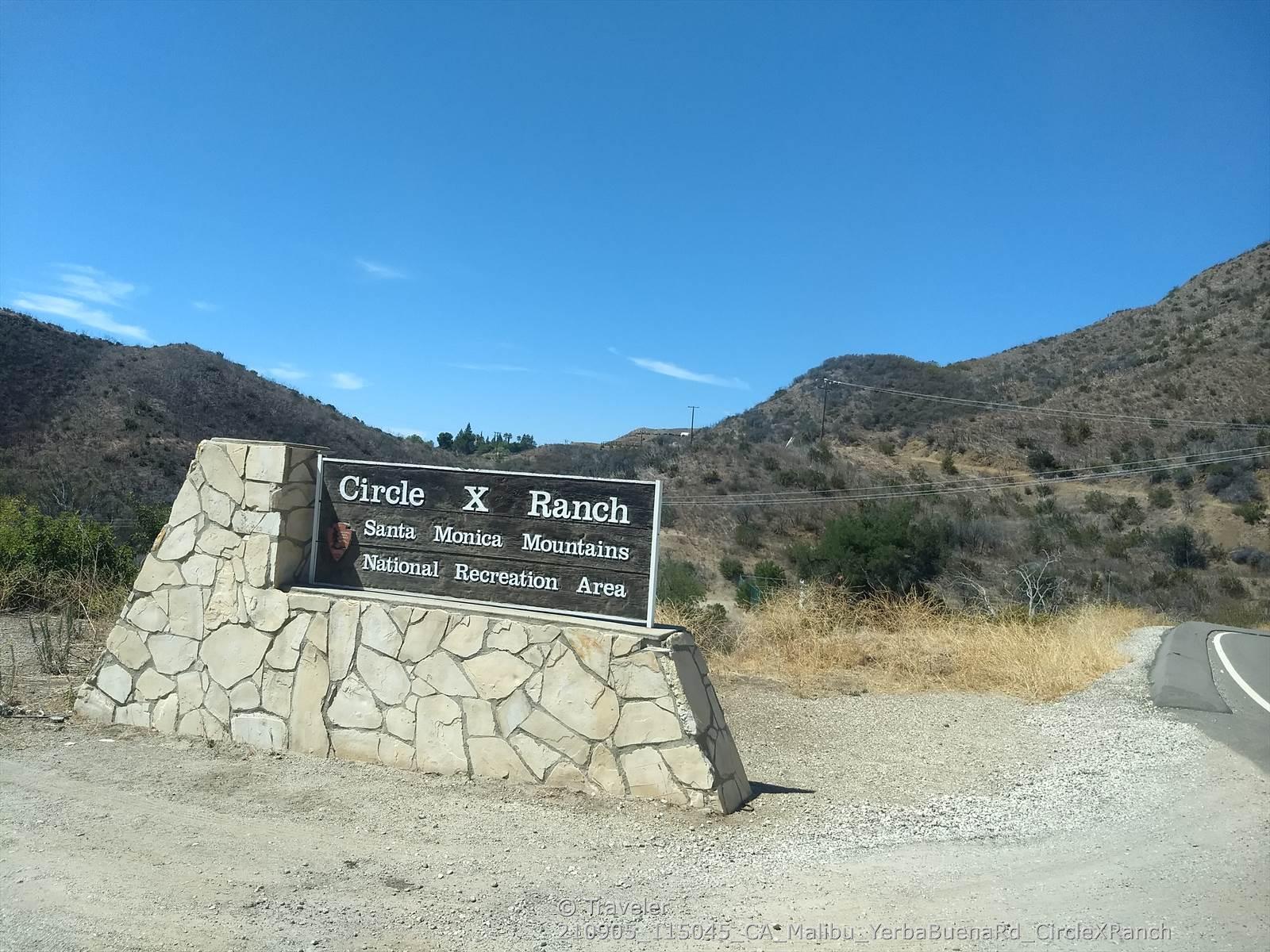 Stone sign in a dry, hilly landscape under a clear blue sky.