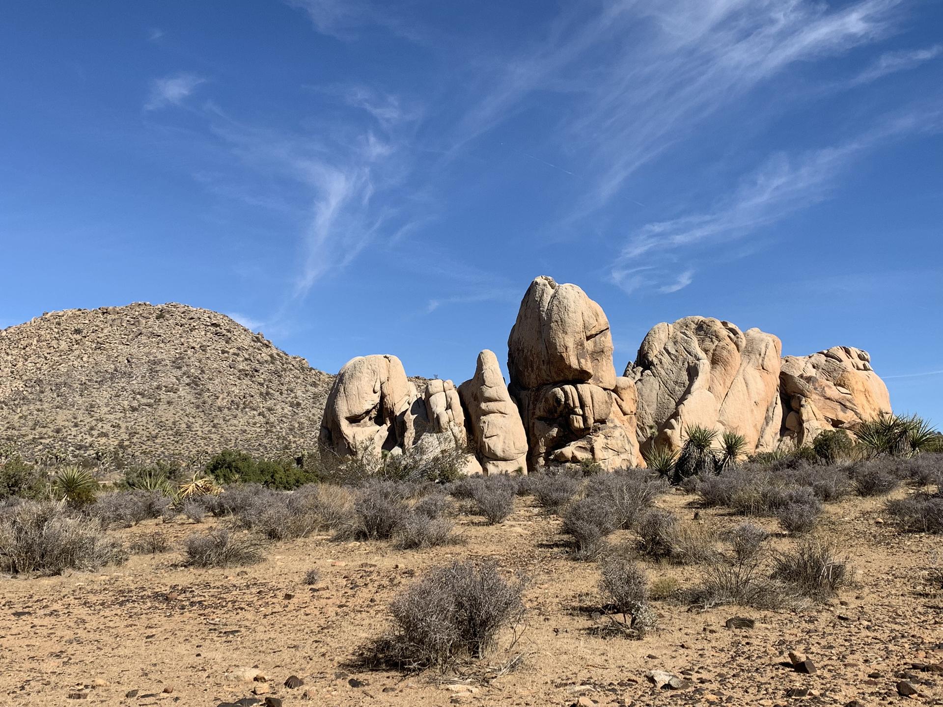 Large, light-colored rock formations in a desert under a clear blue sky.