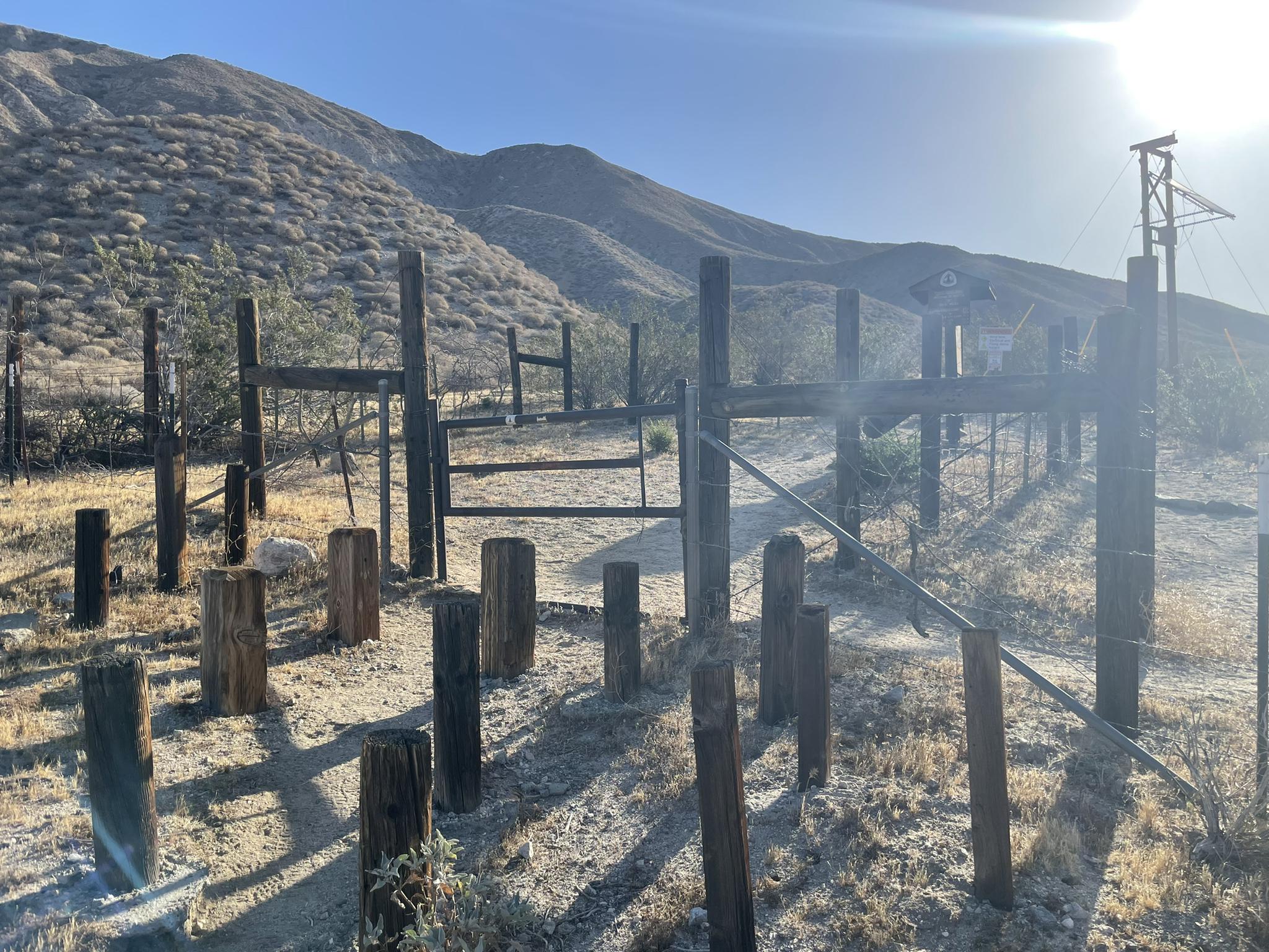 Wooden posts and fences in a sunny, arid landscape with hills.