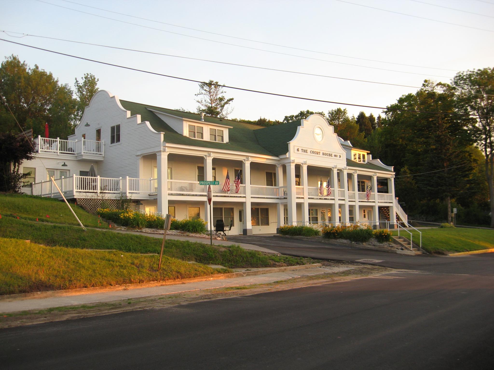 Large white building with multiple porches and a green roof at sunset.