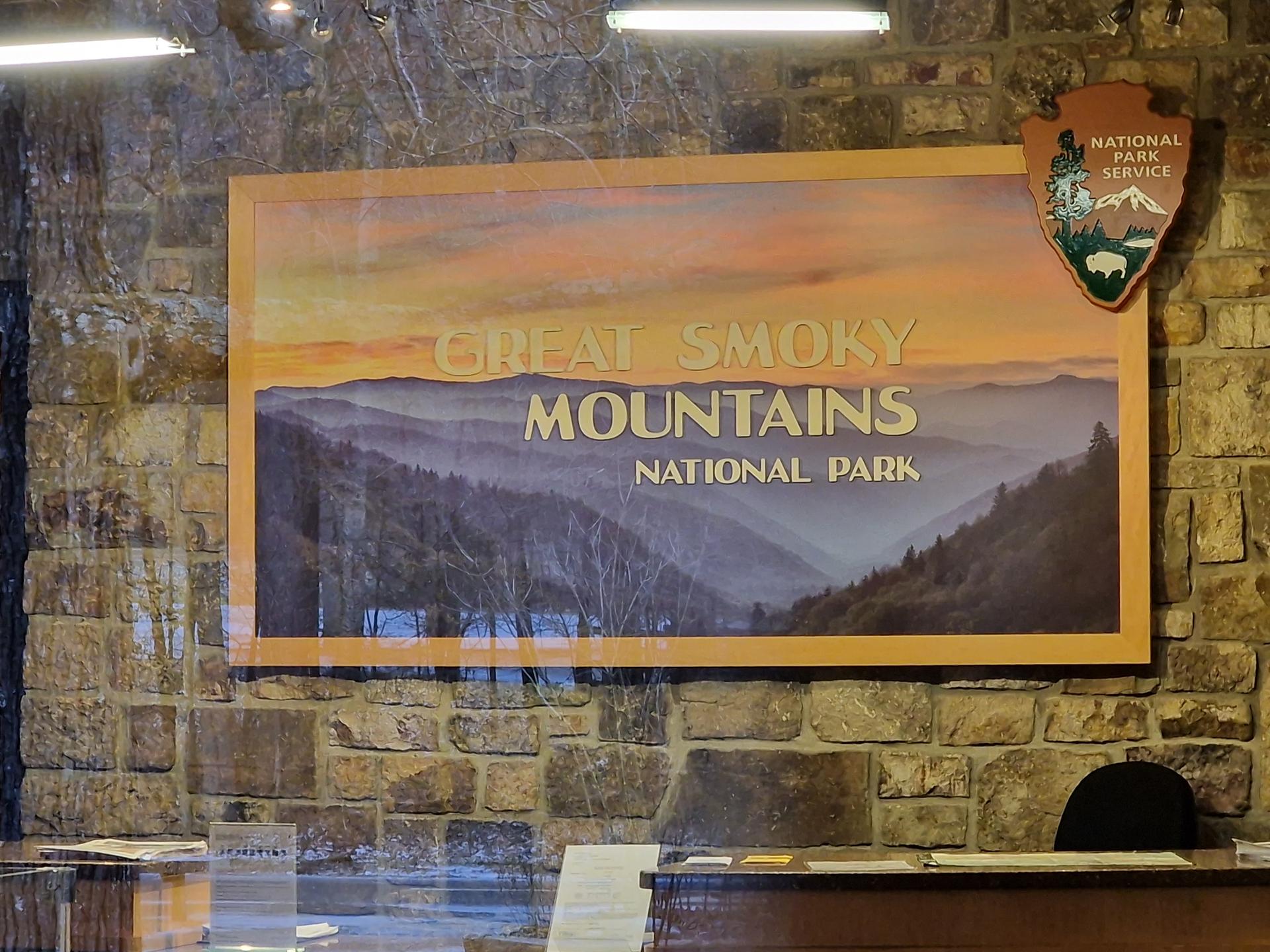 Framed picture of misty mountains on a stone wall indoors.