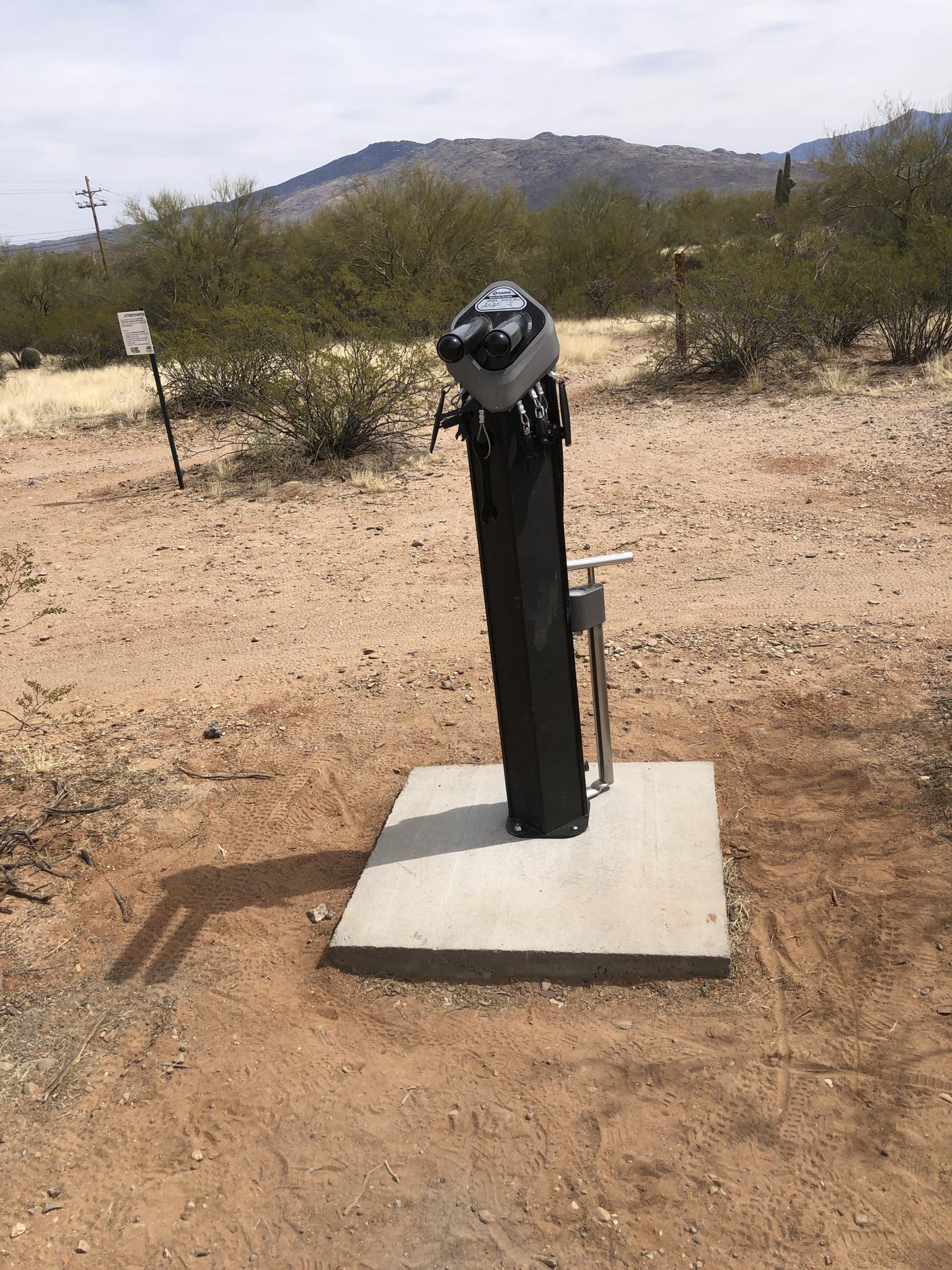 Outdoor bike repair station in a sunny, arid, mountainous landscape.