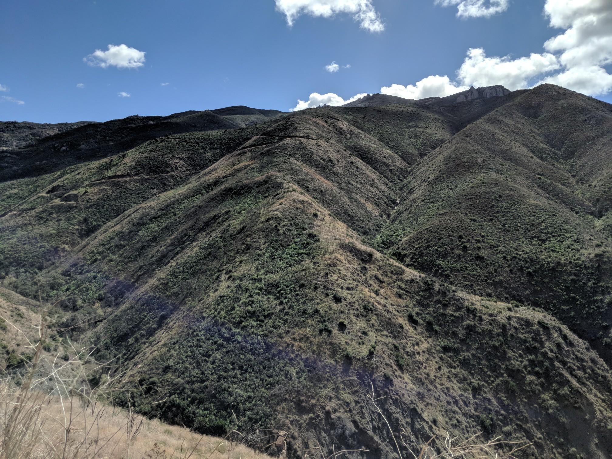 Steep, green-covered mountainsides with a partly cloudy blue sky above.