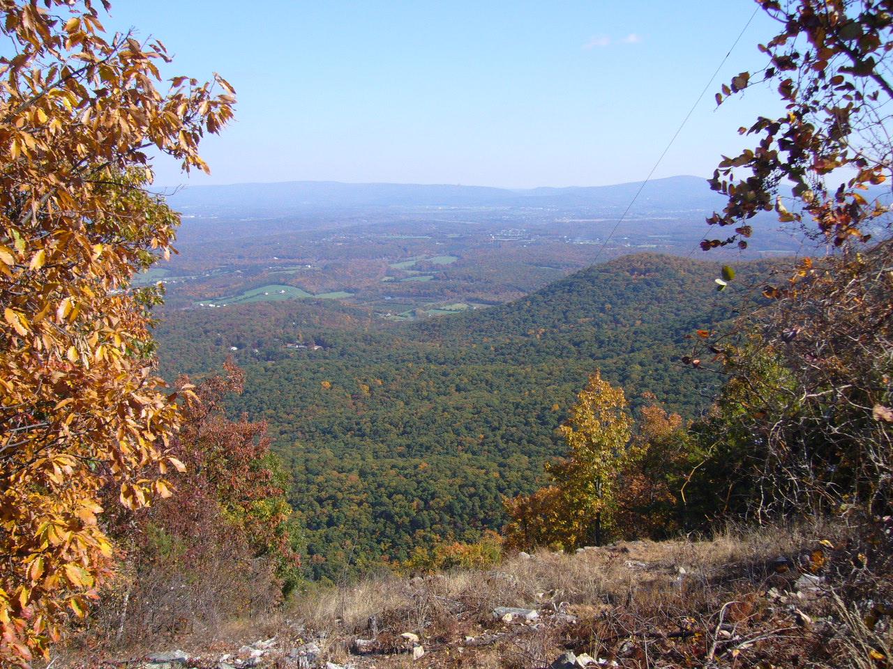 Autumn mountain vista with a vast valley below, framed by fall foliage.