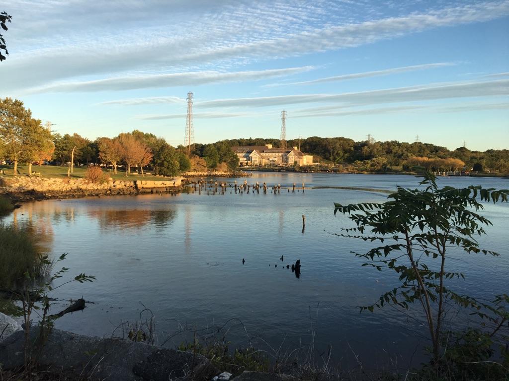 A wide water body with distant buildings and power lines under a cloudy sky.