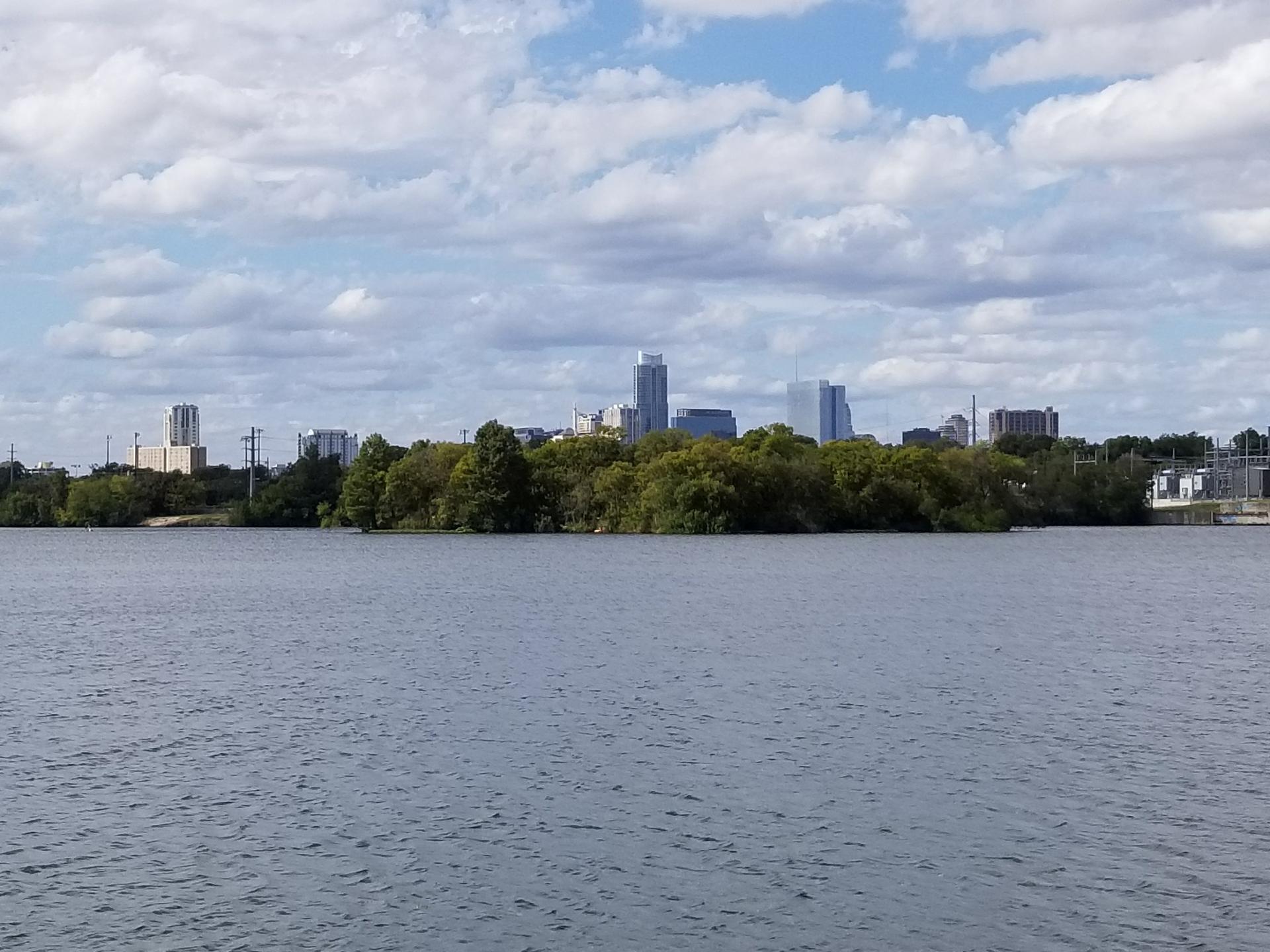 City skyline visible across a wide body of water under a partly cloudy sky.