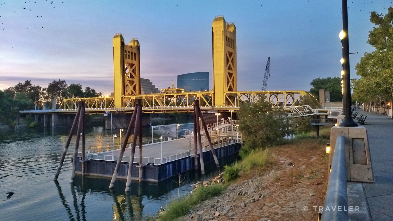 A yellow truss bridge with towers over a river at dusk, with a dock. - Sacramento River loop from Downtown Sacramento via Clarksburg Trail