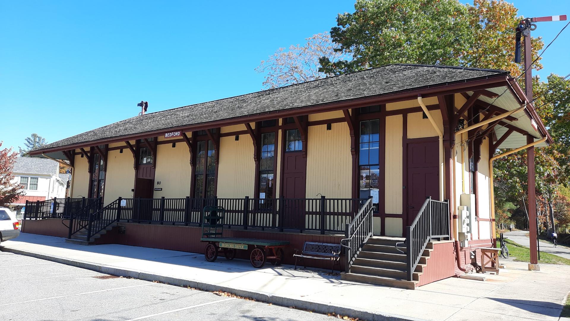 Historic yellow and brown building with a long porch on a sunny day.