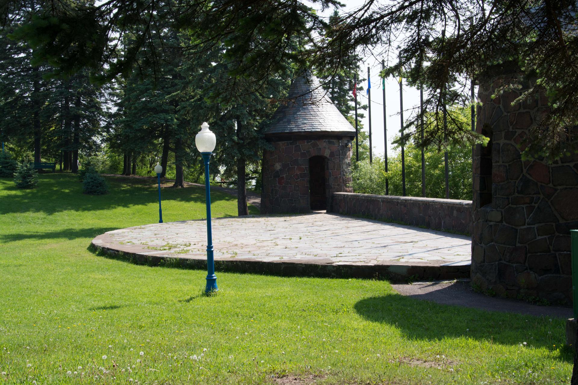 Stone turrets and a paved circular area in a sunny park.