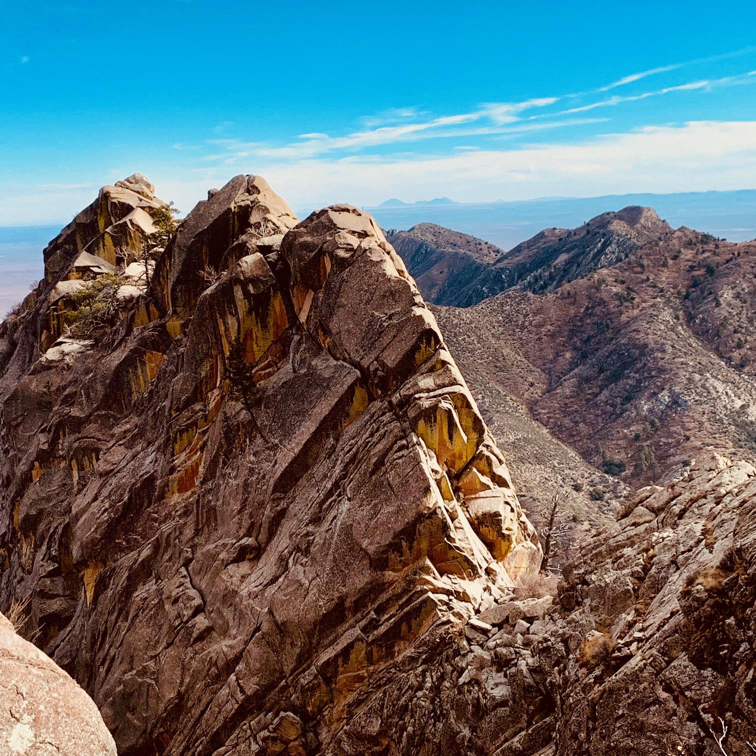 Dramatic, jagged mountain peaks under a vibrant blue sky with scattered clouds.