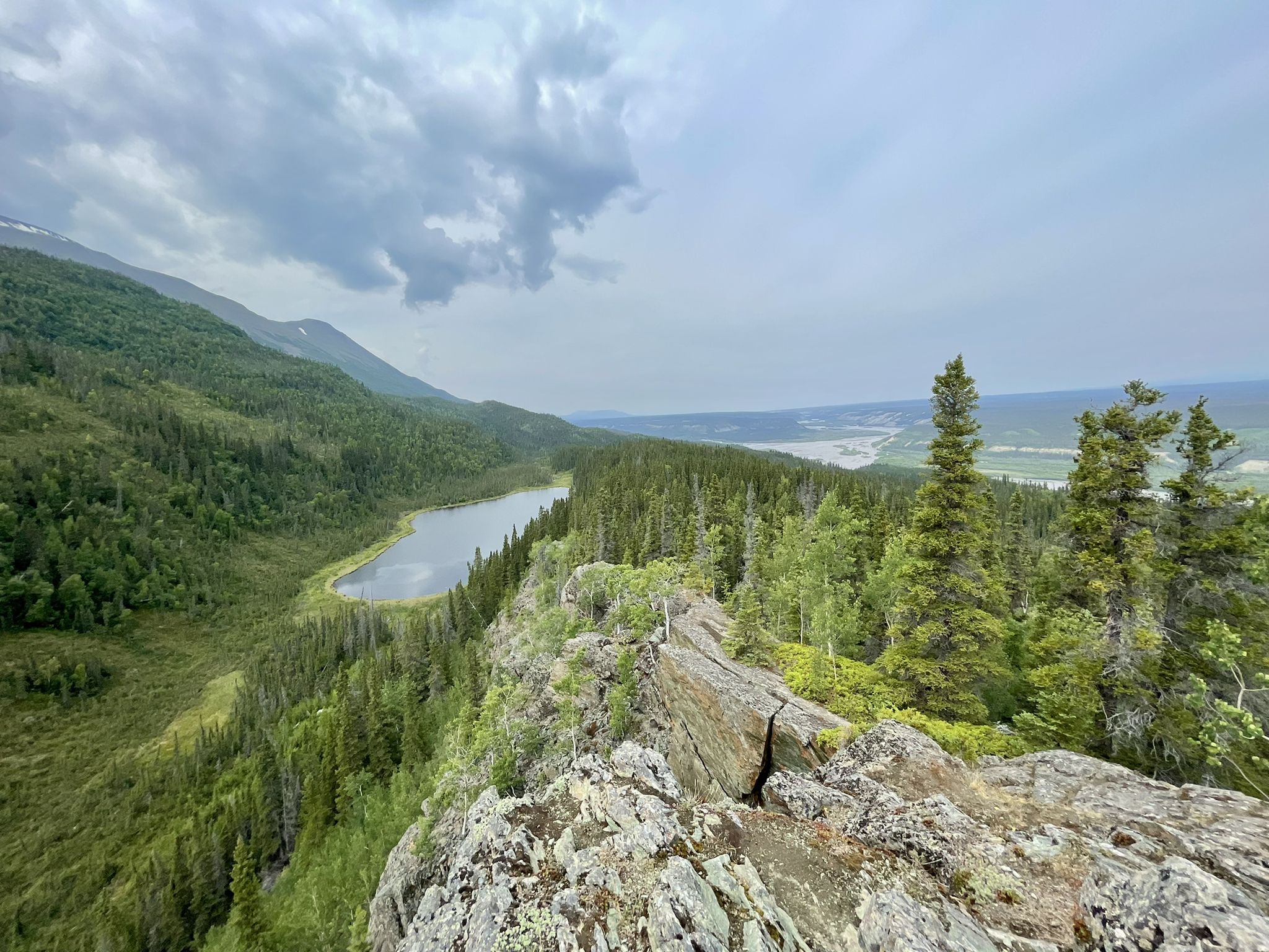 View from a rocky cliff overlooking a serene lake and vast green forest. - Liberty Falls Trail