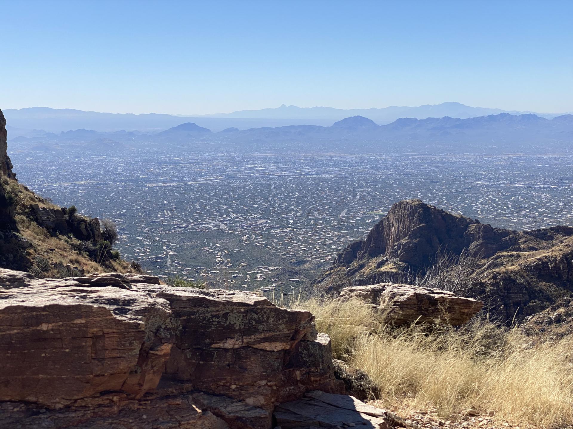 Panoramic view of a sprawling city in a valley from a rocky mountain overlook.