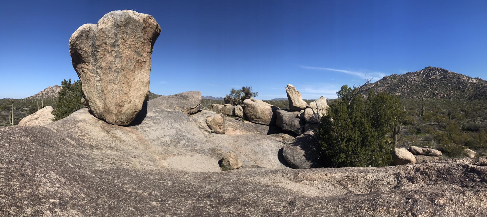 Unique large rock formation on a sunny, rocky desert landscape.