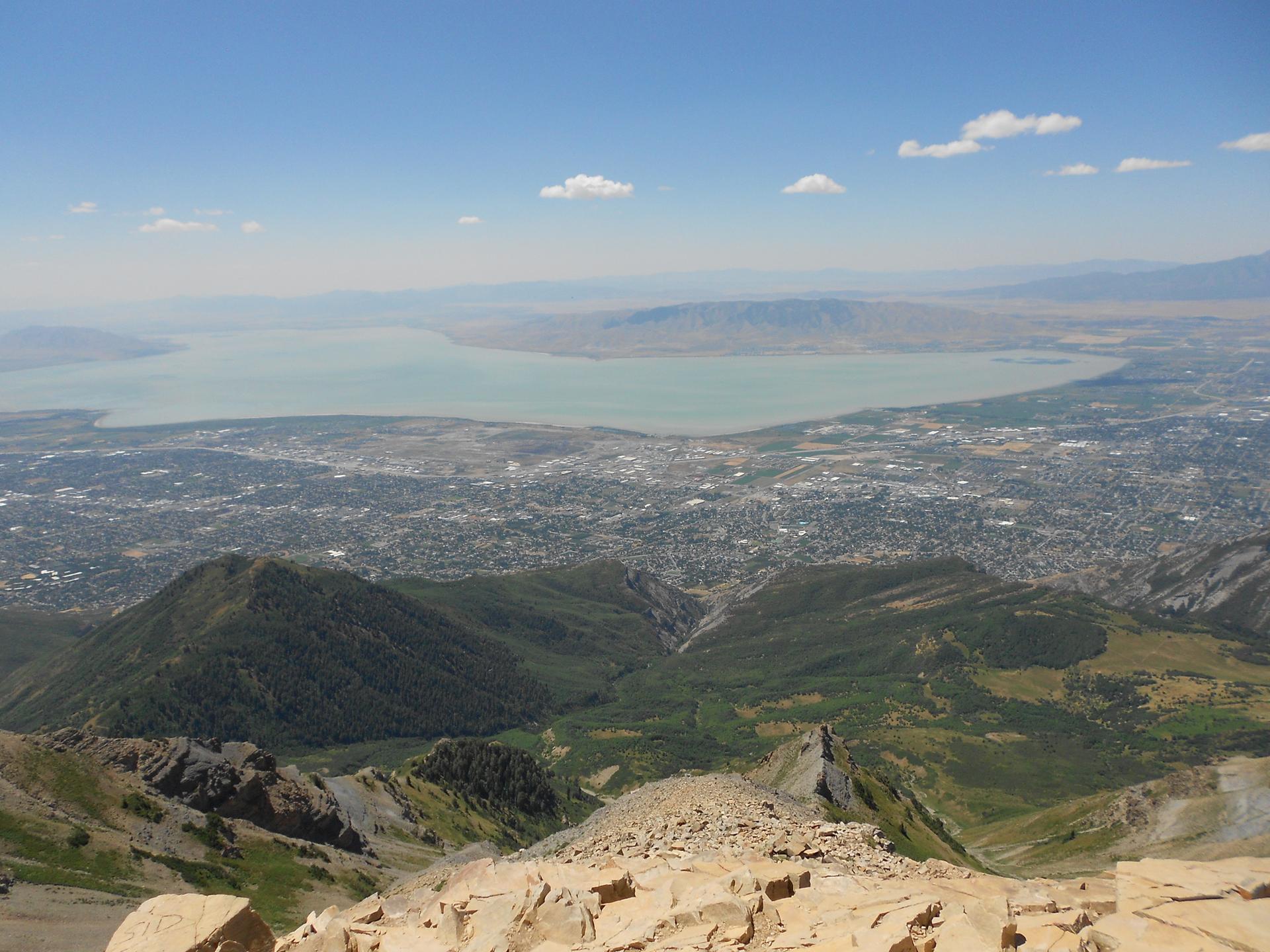 Expansive aerial view of a city, large lake, and distant mountains.