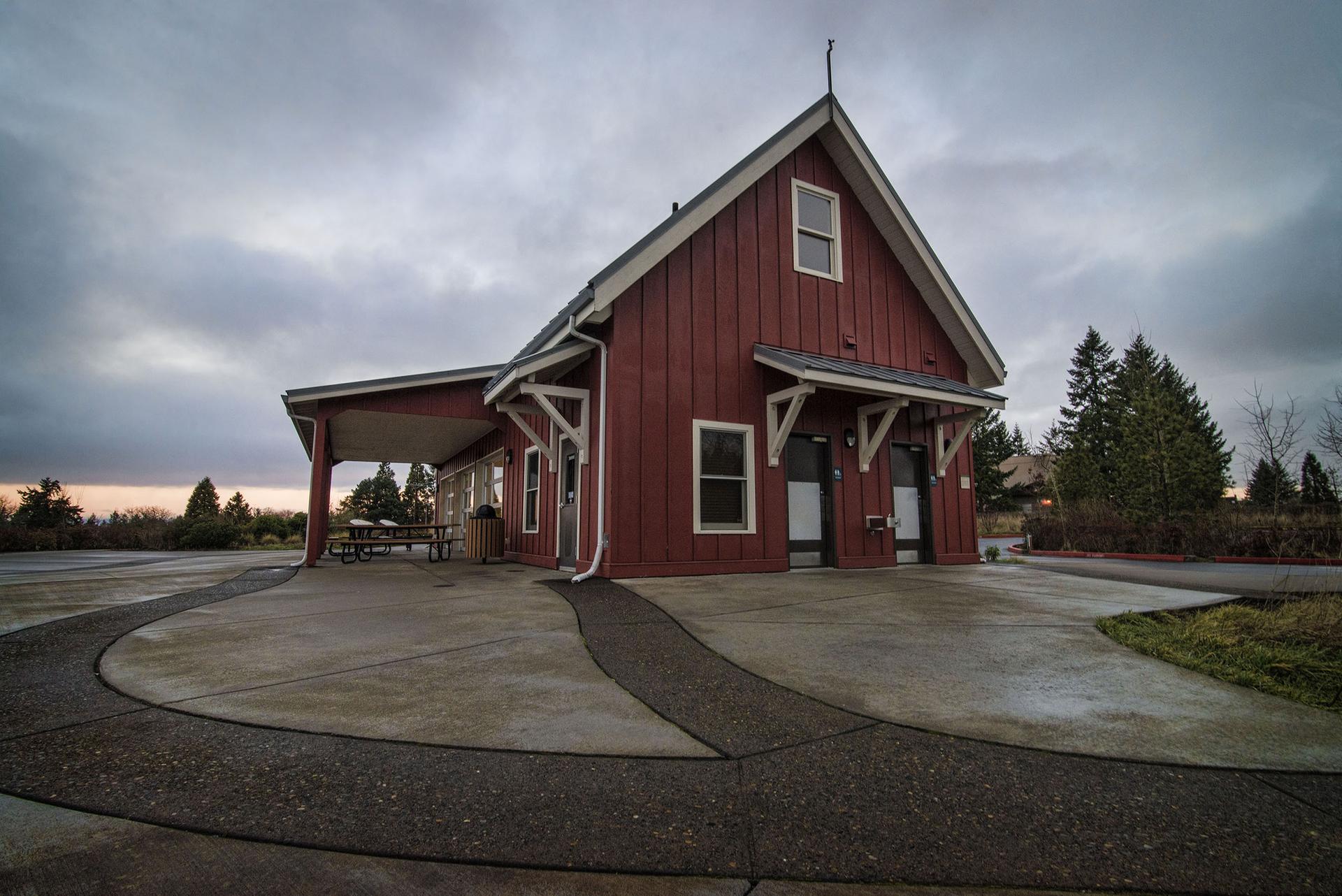 Red barn-style building with concrete paths under an overcast sky.
