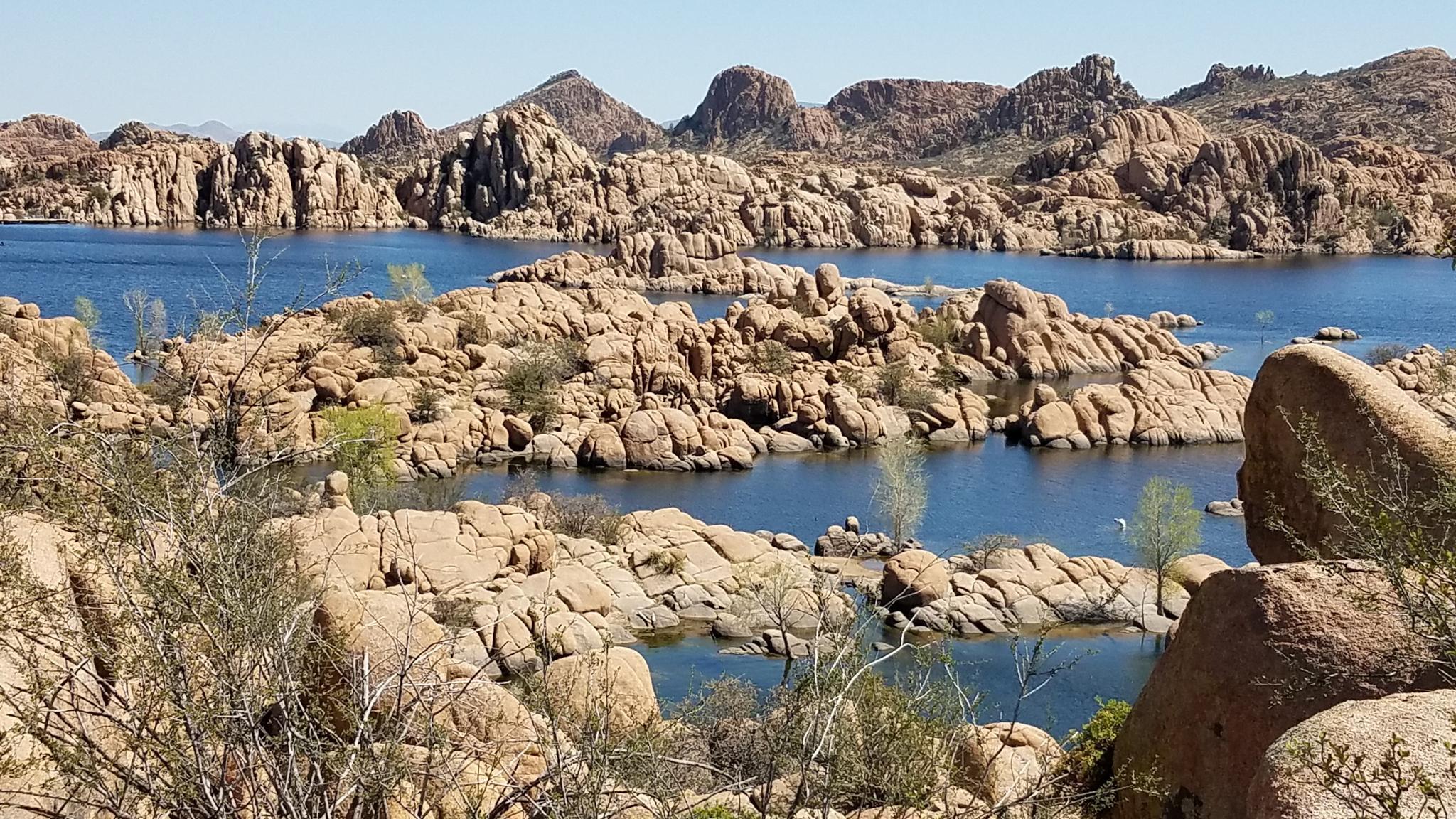 Sunny view of a lake surrounded by numerous large, light-colored rock formations.