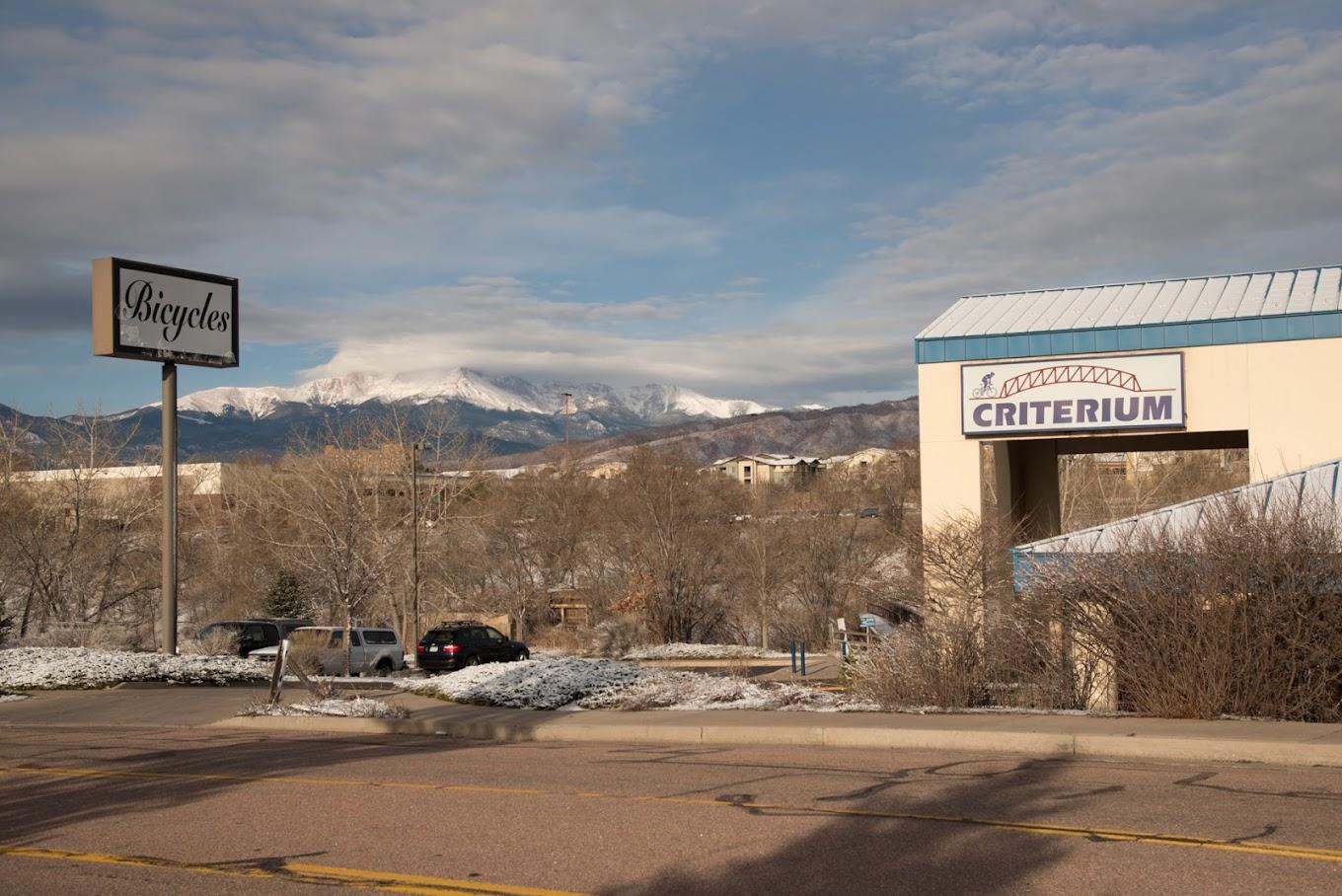 Commercial buildings with snowy ground and distant snow-capped mountains.