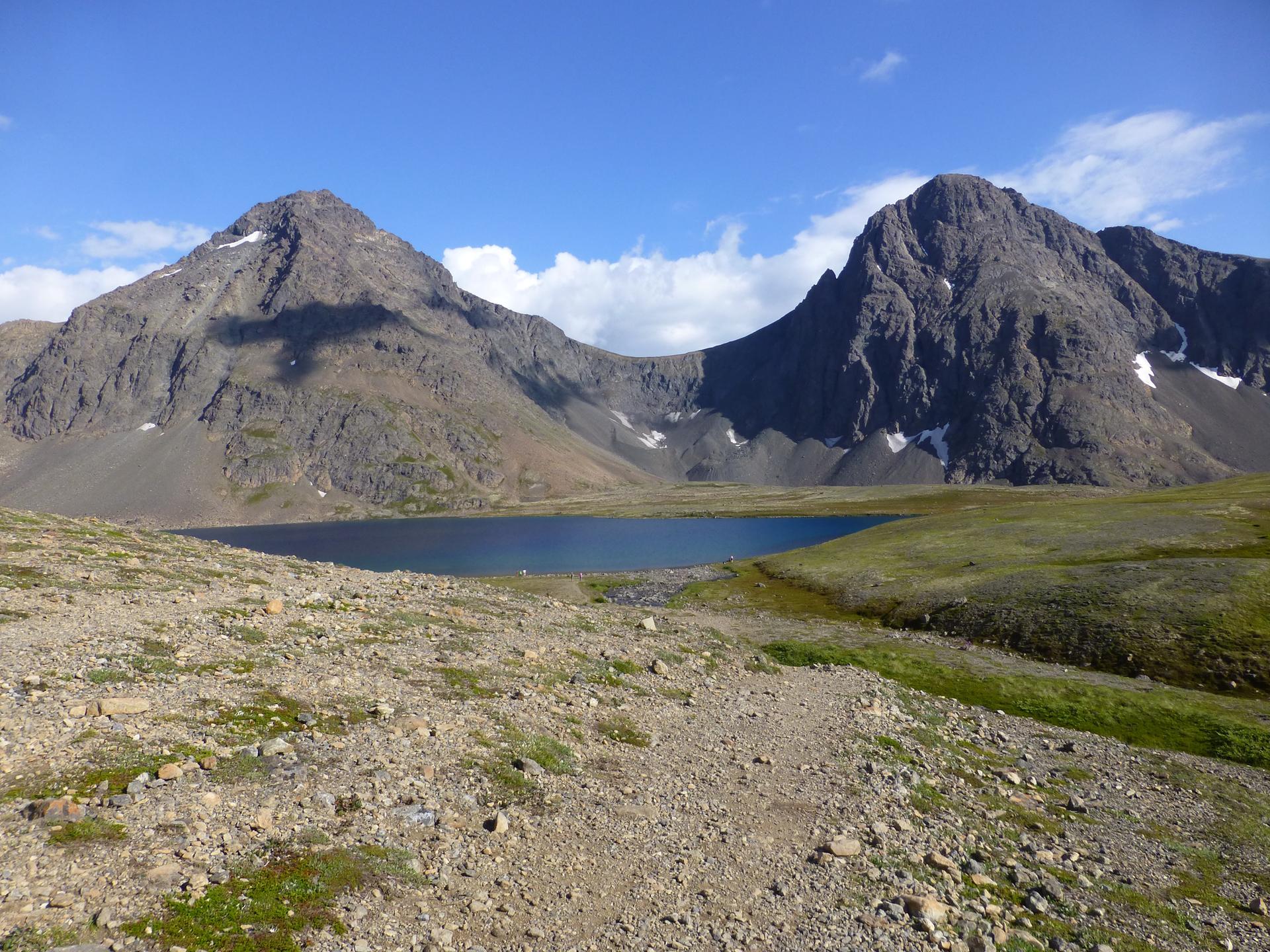 Rocky landscape with a dark blue lake nestled between two large mountains.