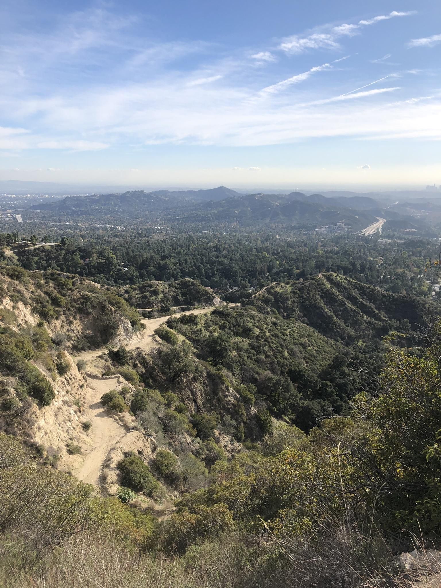 Winding dirt road on a hillside overlooking a vast, hazy valley. - Earl Canyon Motorway Trail