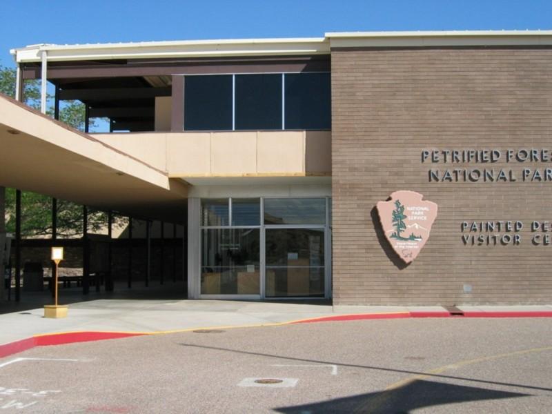 Exterior of a modern visitor center building with a park emblem on the wall.