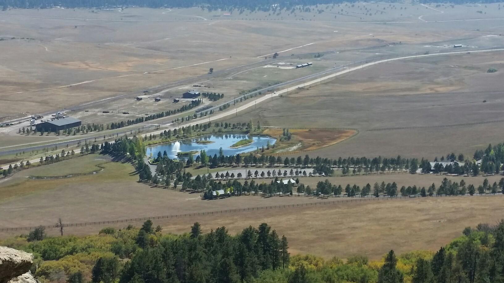 Aerial view of a road, pond, and buildings in a vast, open landscape.
