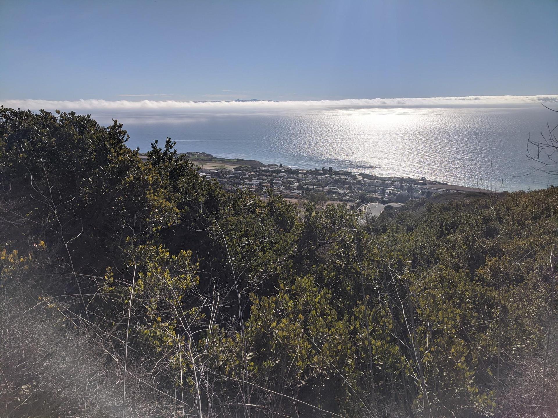 Overlook of a coastal town and ocean under a bright, sunny sky.