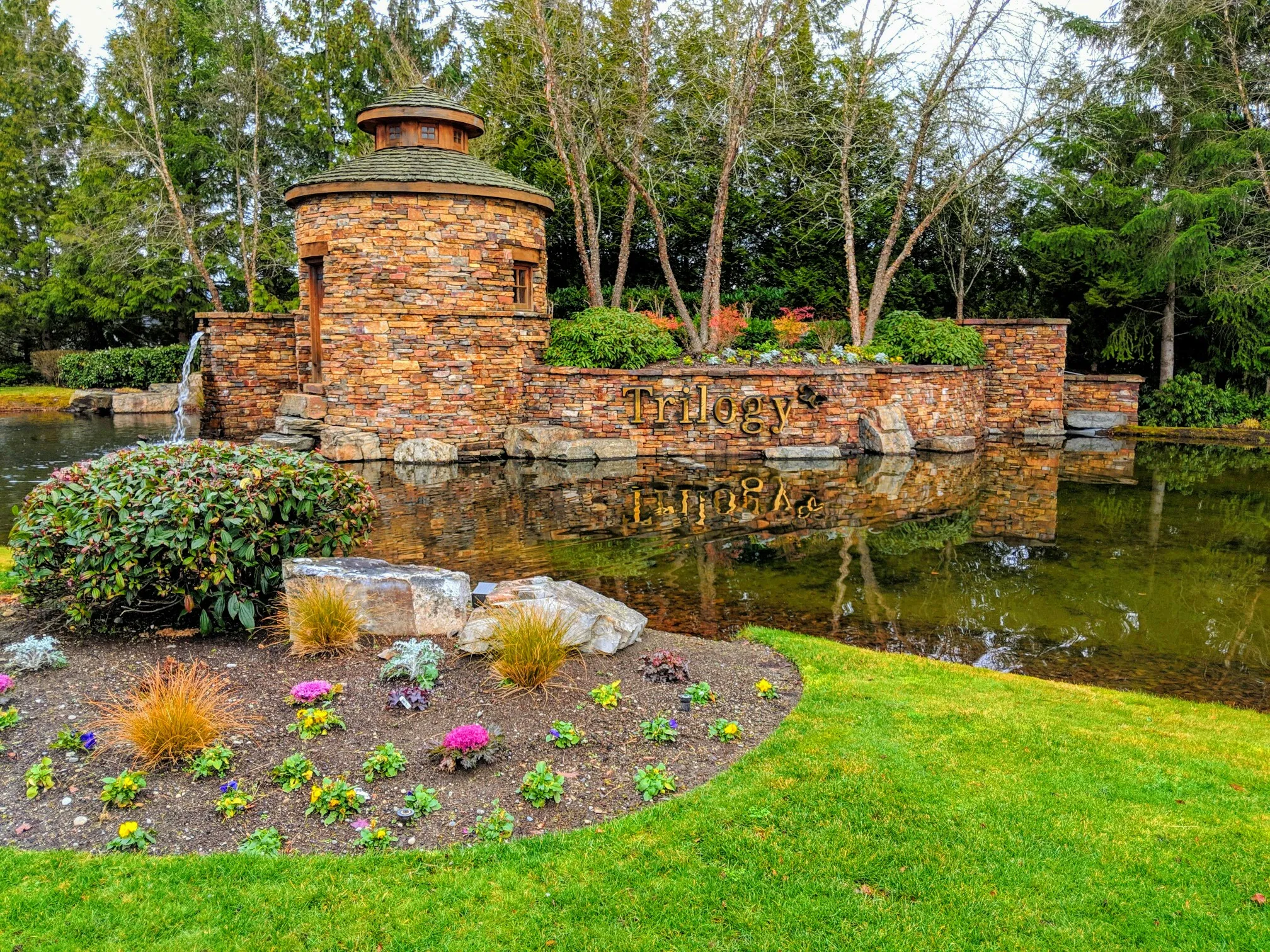 A stone entrance feature with a waterfall, reflective pond, and green landscaping. - Redmond Ridge Trail loop from Redmond Watershed Preserve