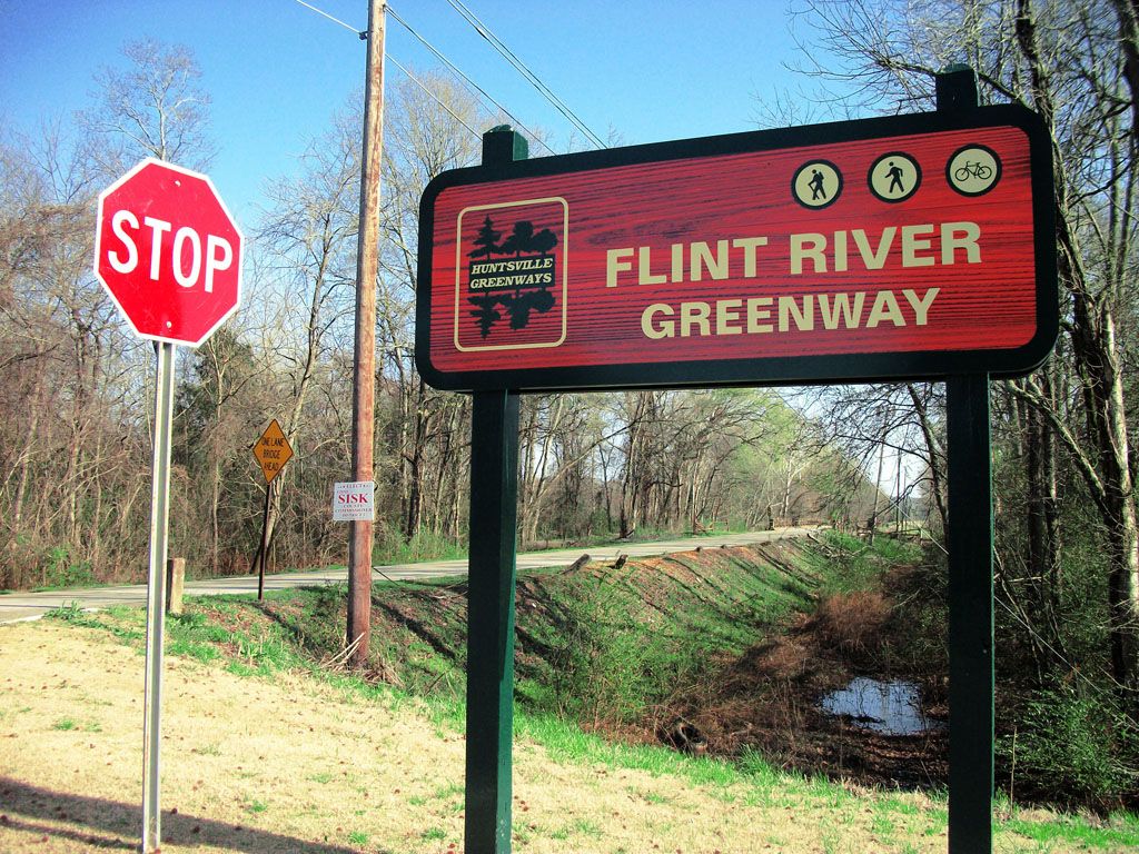 Greenway sign and stop sign next to a dirt path in a sunny, wooded area. - Big Cove Creek and Flint River Greenways Loop