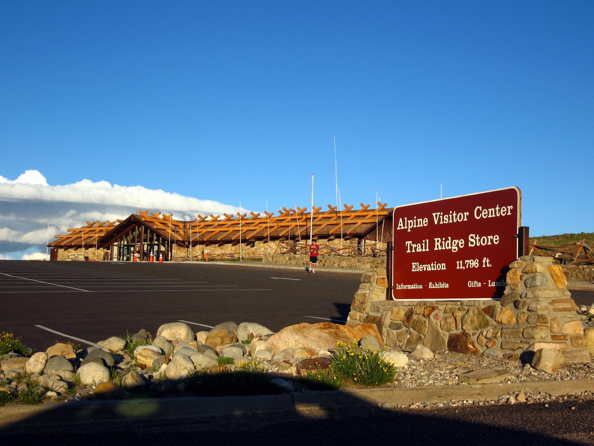 A visitor center building and sign under a bright blue sky.