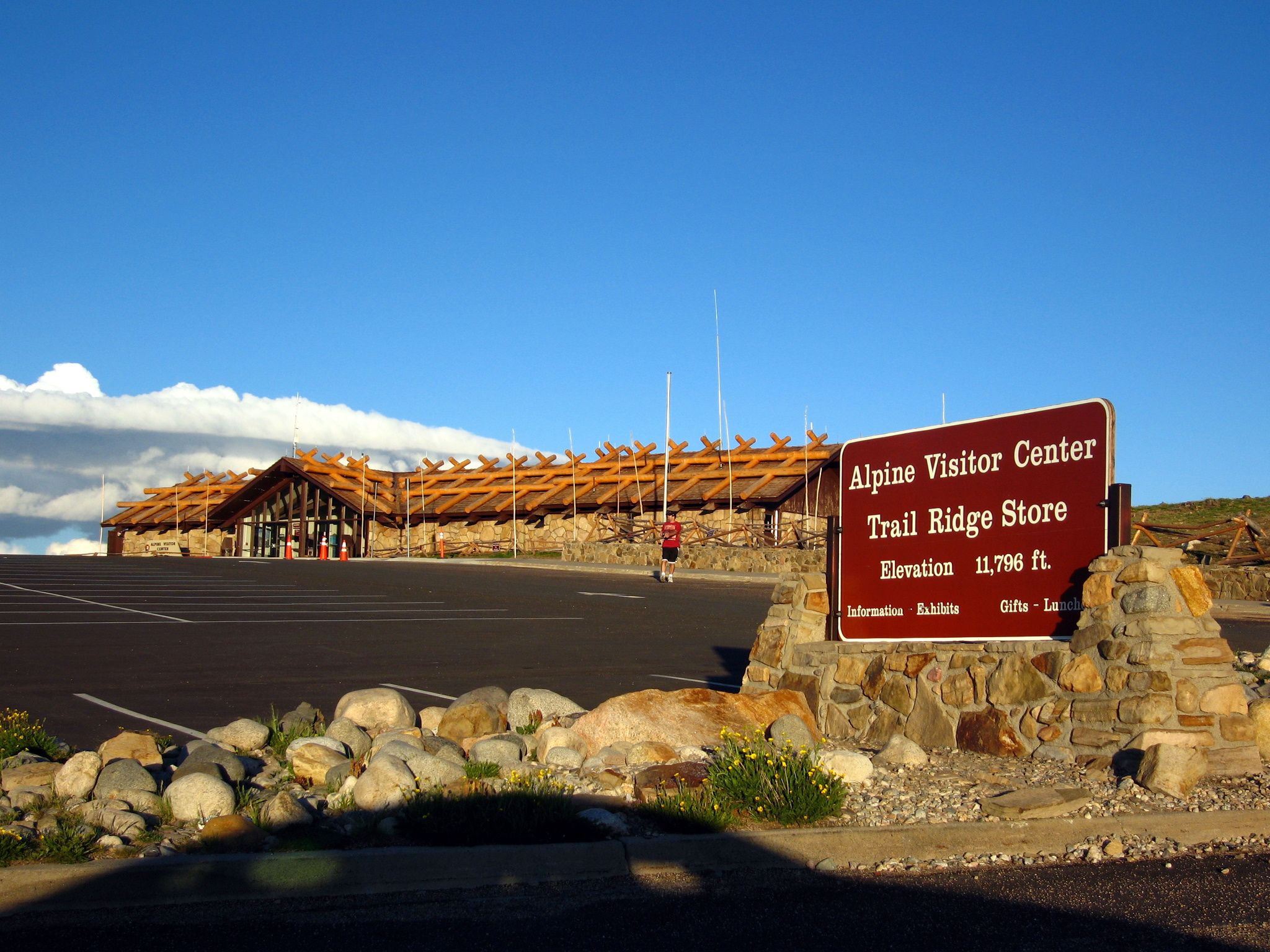 A visitor center building and sign under a bright blue sky. - RMNP/Alpine Visitor Center