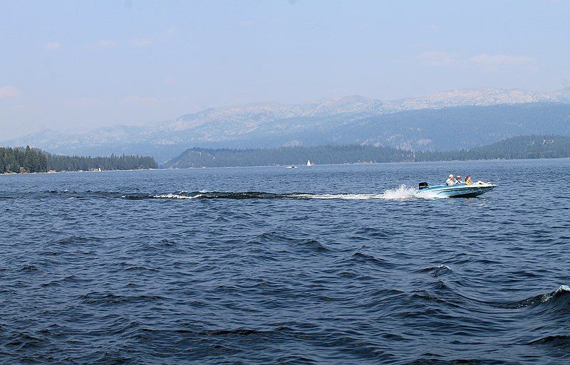 Motorboat with people speeding across a large lake with forested shores and mountains. - Huckleberry Trail loop from Barbara Morgan Elementary School