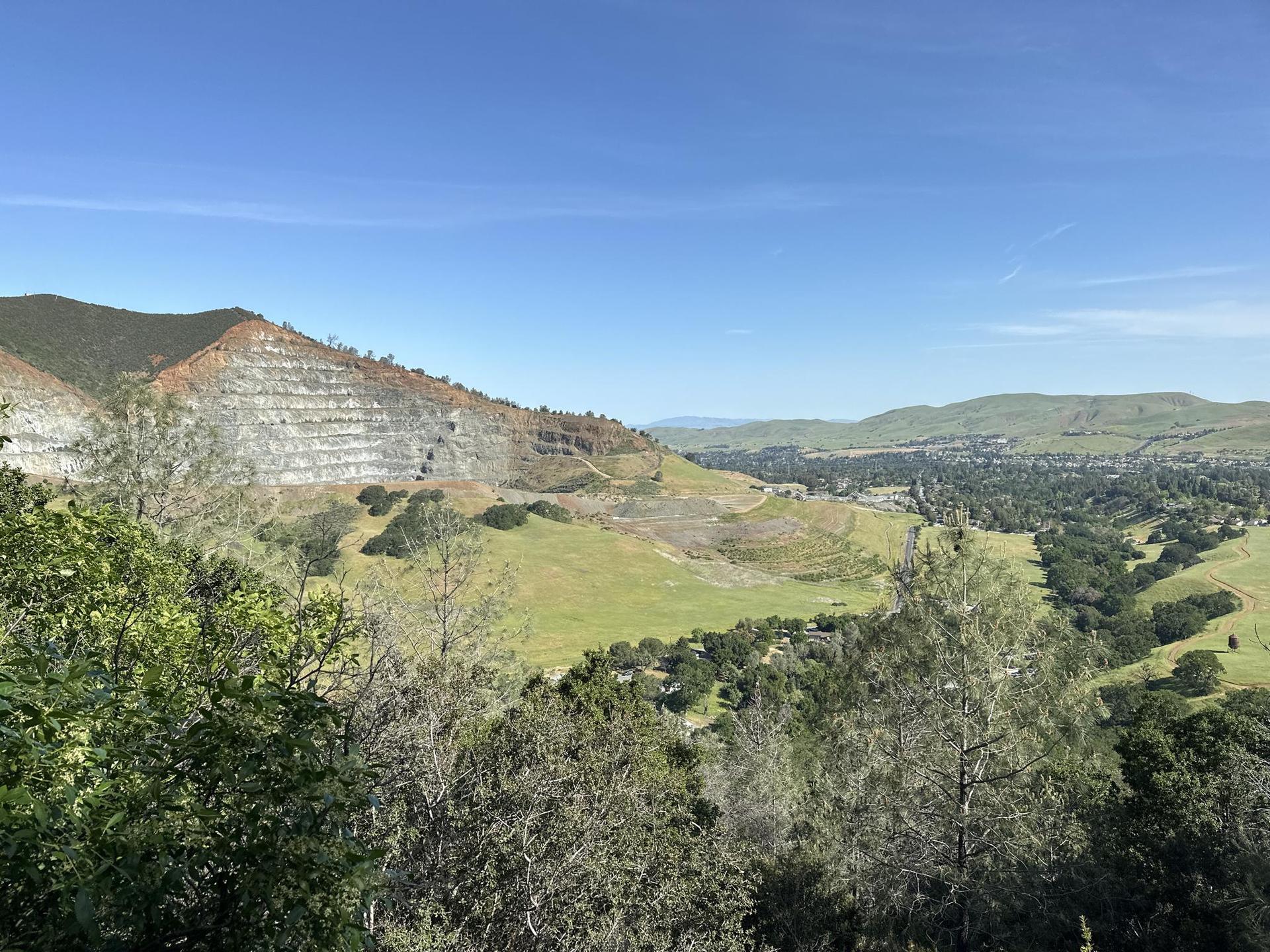 Green valley and forested hills with a terraced mountain under a clear blue sky.