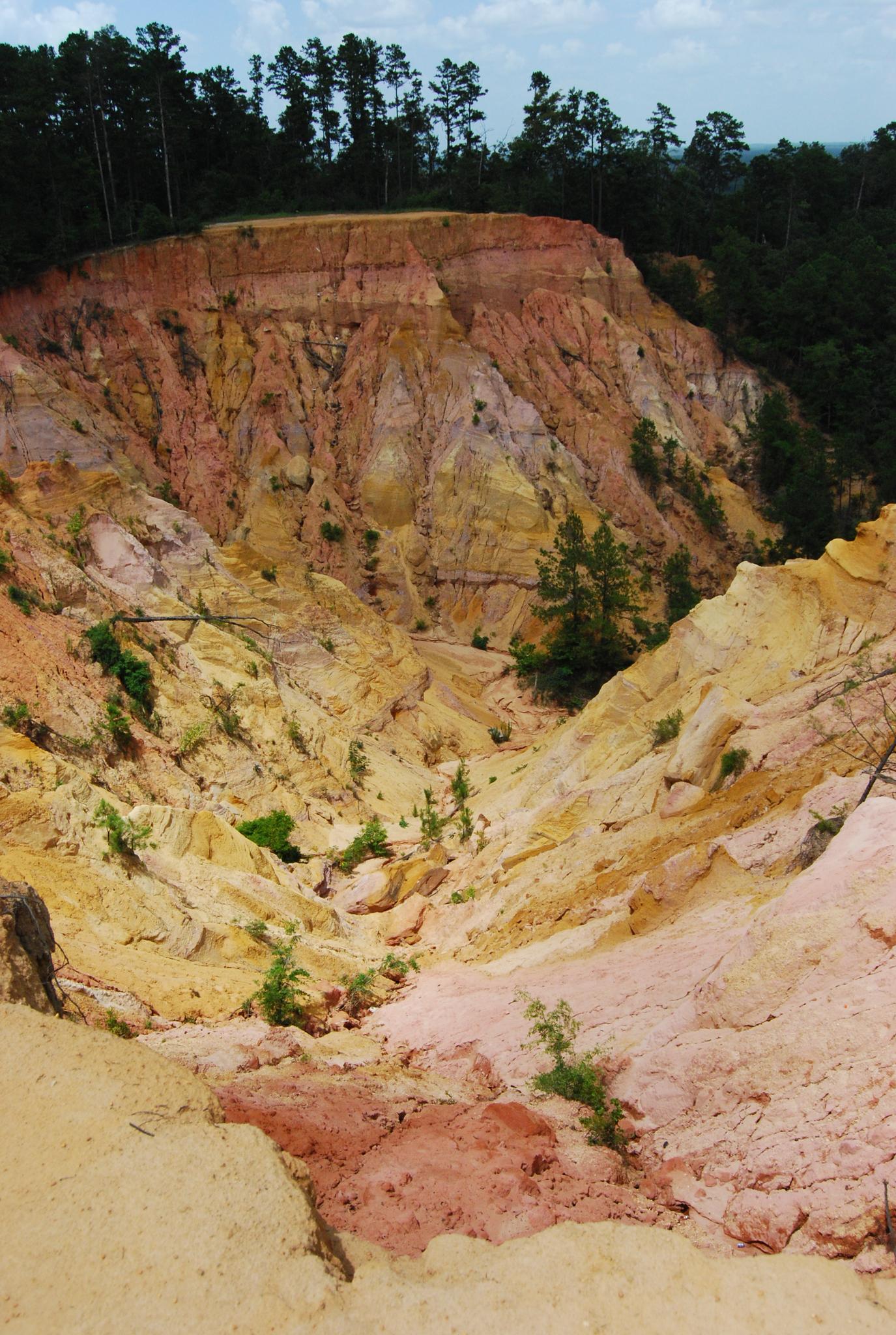 Dramatic landscape of multi-colored eroded cliffs under a bright sky.