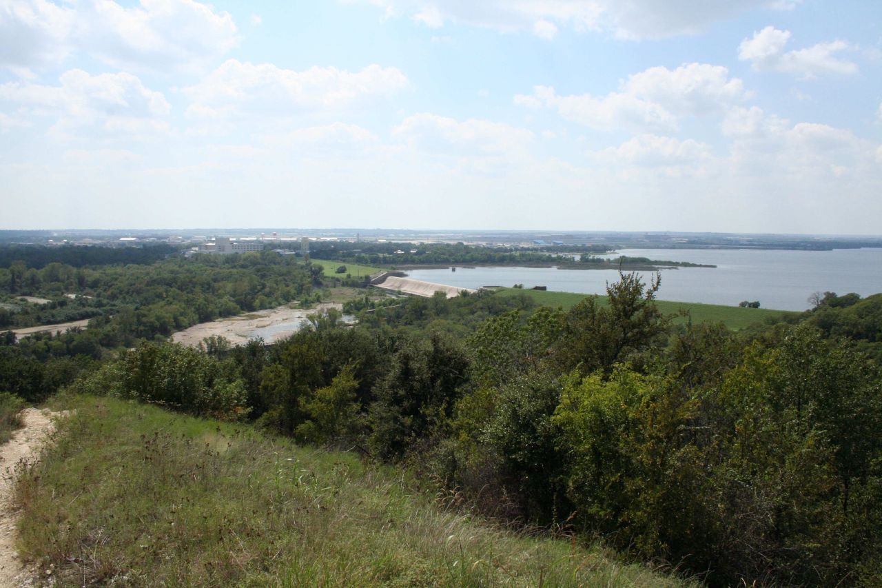 Panoramic view of a large lake surrounded by green trees under a cloudy sky. - Lone Wolf and The Dam Drop Trail Loop