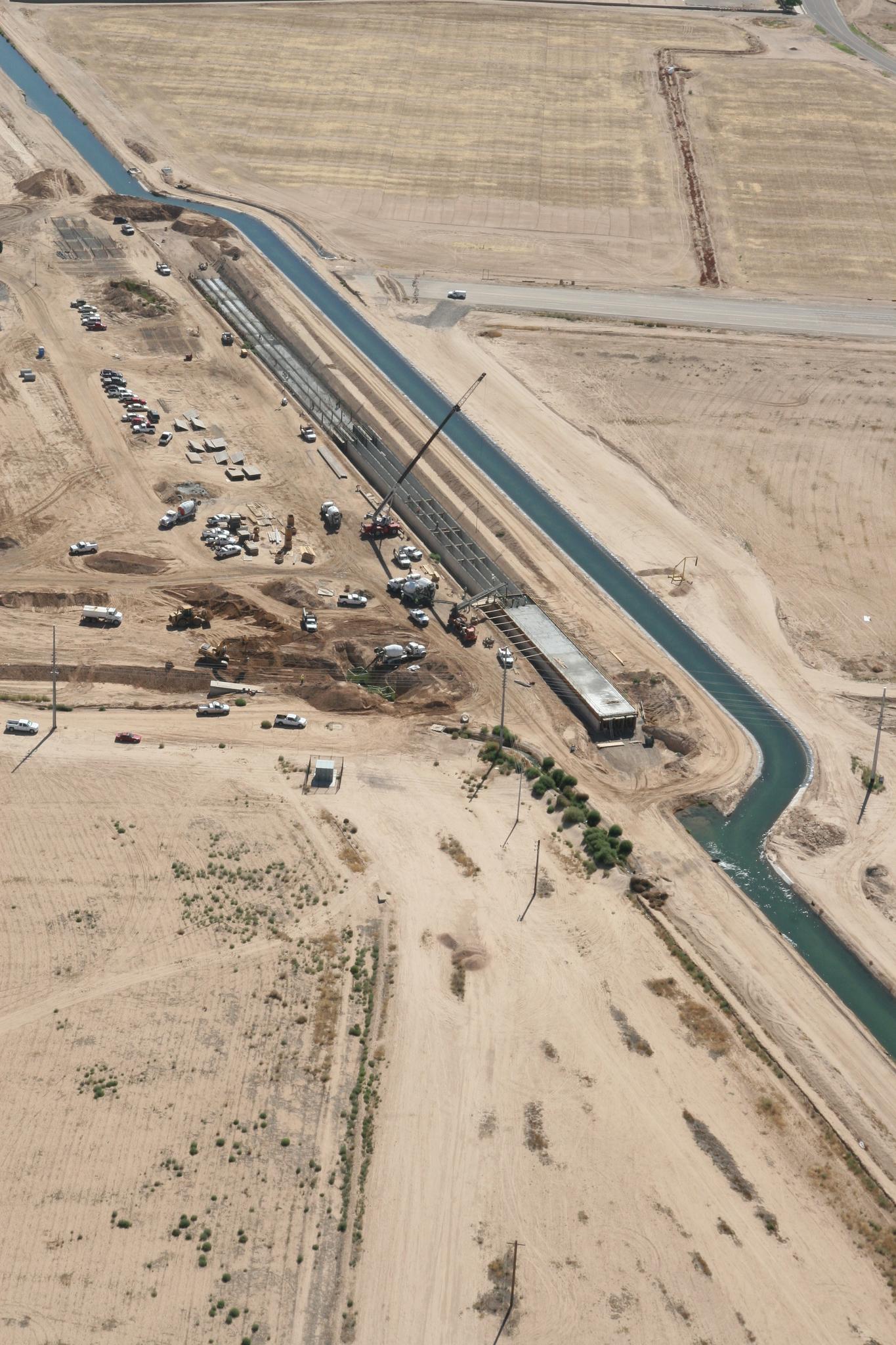 Aerial view of a long construction trench and canal in dry, flat terrain.