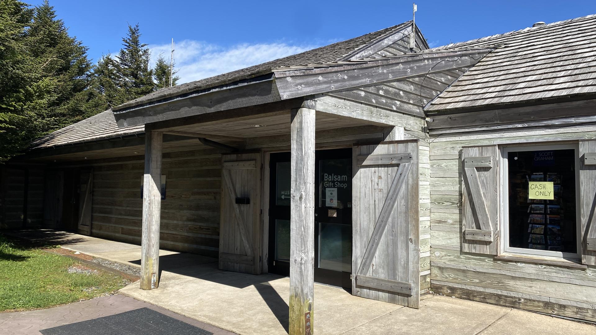 Weathered wooden building with a covered entrance under bright sunlight.
